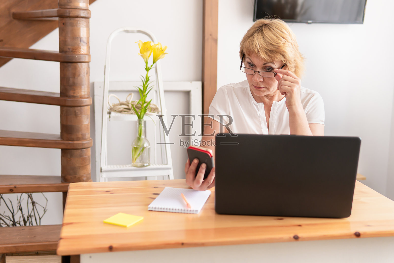 办公室里的一位女士正坐在书桌旁，窗户边放着一台笔记本电脑。照片摄影图片