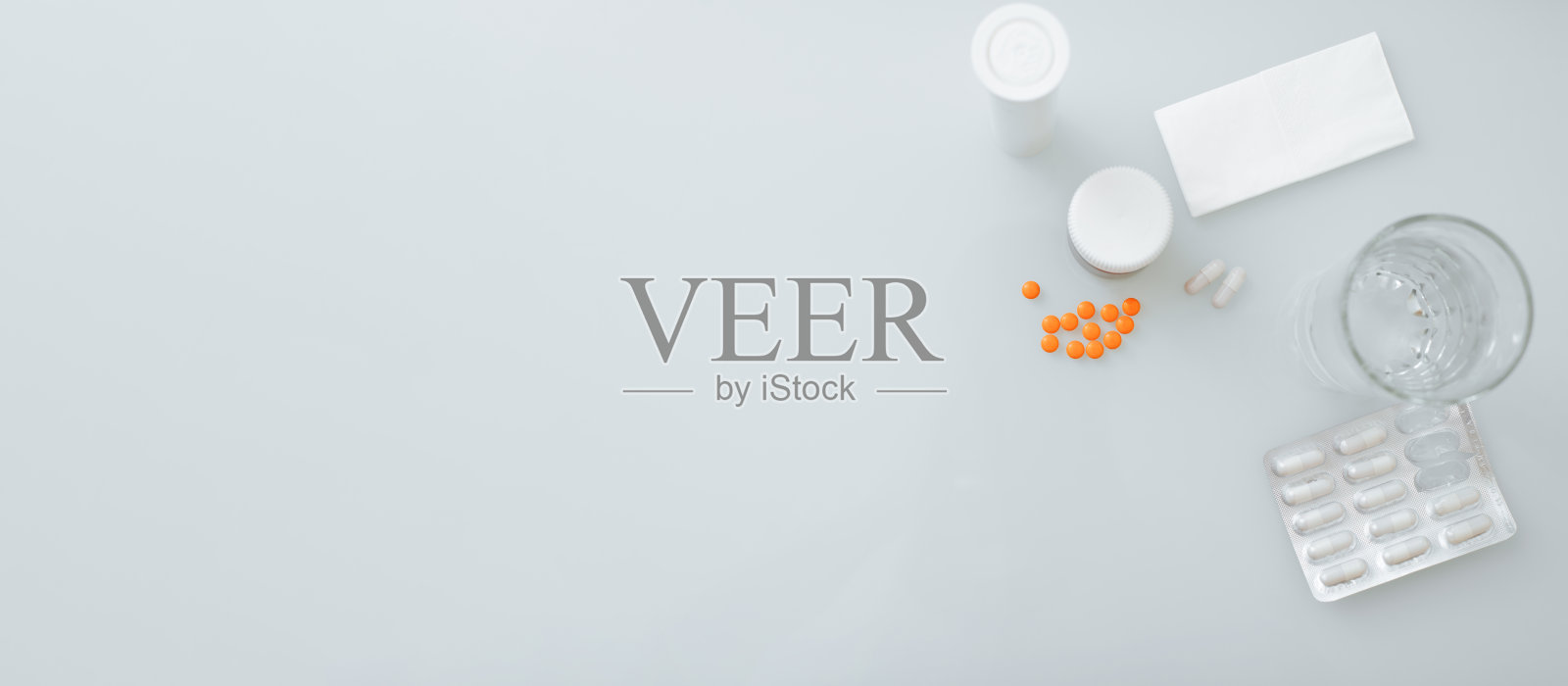 保健、医学和框架学概念。俯视图的药丸，一瓶药，一杯水在桌子上。带有复制空间的处理横幅照片摄影图片