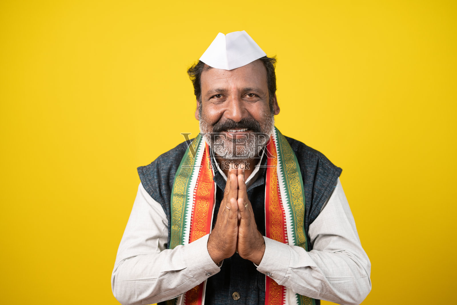 印度政治家用合十礼打招呼——黄色背景上表示欢迎的手势。照片摄影图片