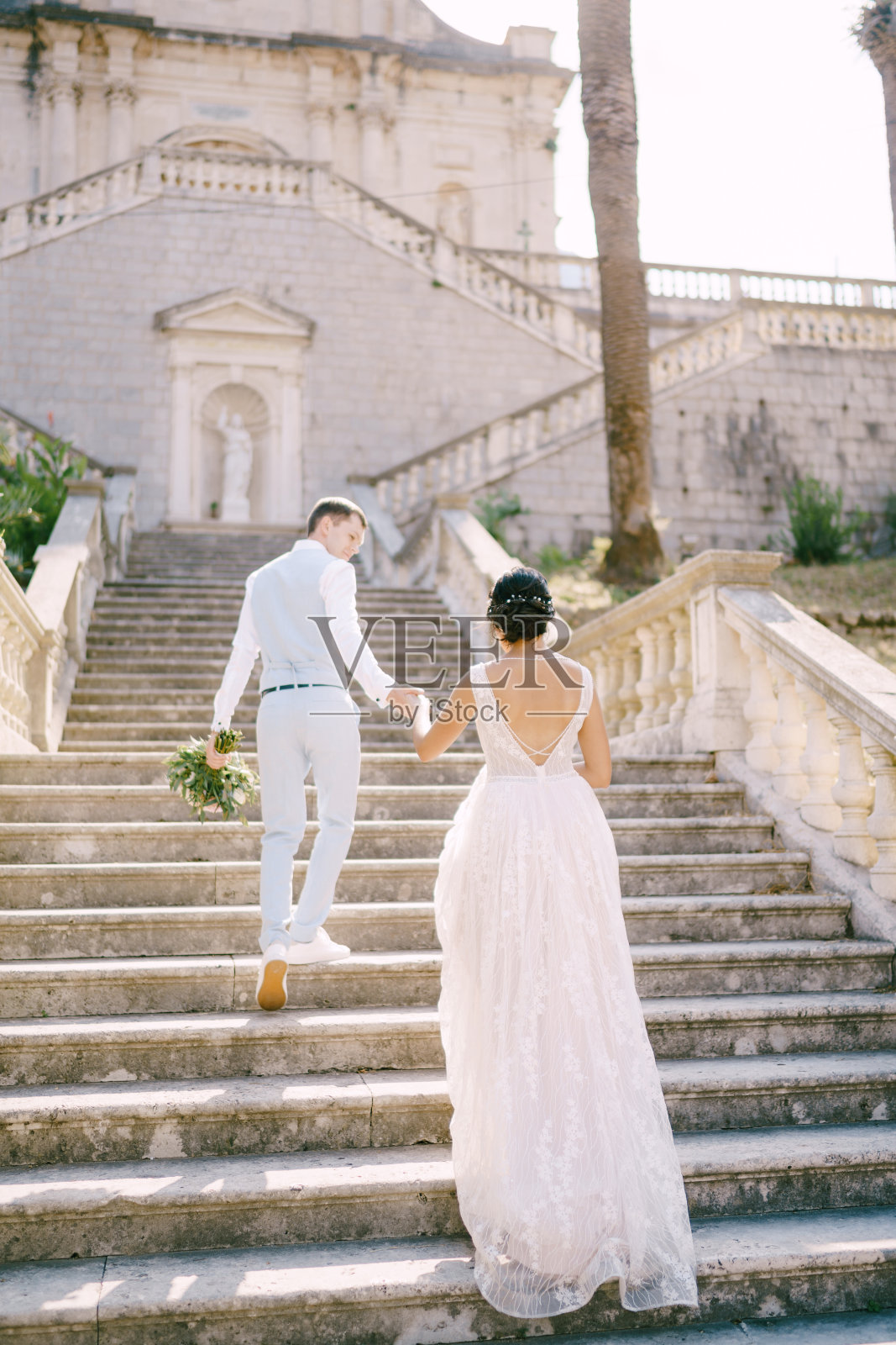 新郎和新娘手牵着手爬上圣母玛利亚诞生教堂的楼梯照片摄影图片