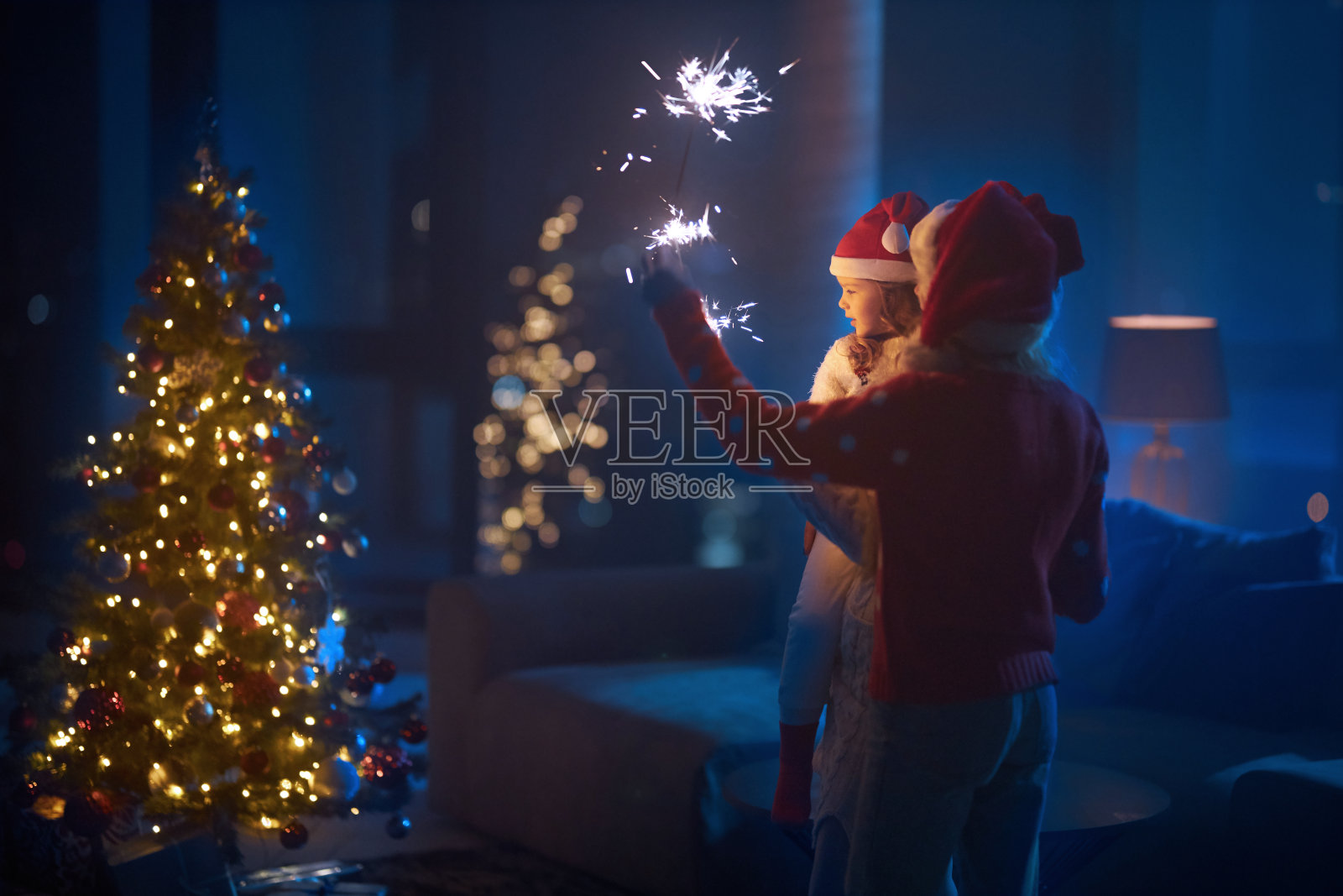 两姐妹拿着烟火站在圣诞树旁照片摄影图片