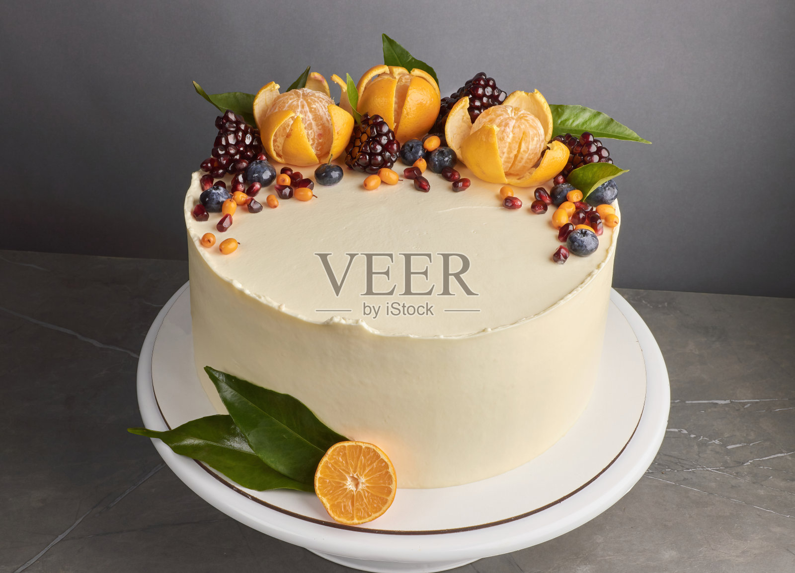 美味的白色蛋糕装饰石榴，橘子，蓝莓，灰色背景照片摄影图片