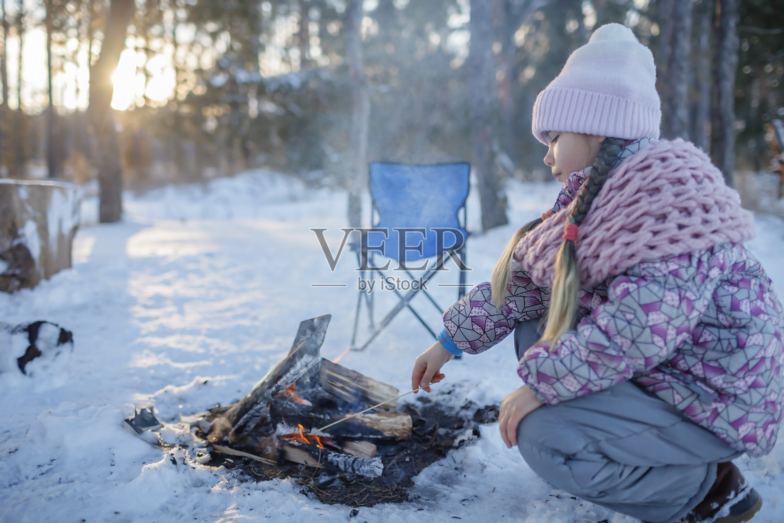 穿着冬衣的女孩在冰雪覆盖的森林里生火取暖，周末的家庭冬季旅行照片摄影图片