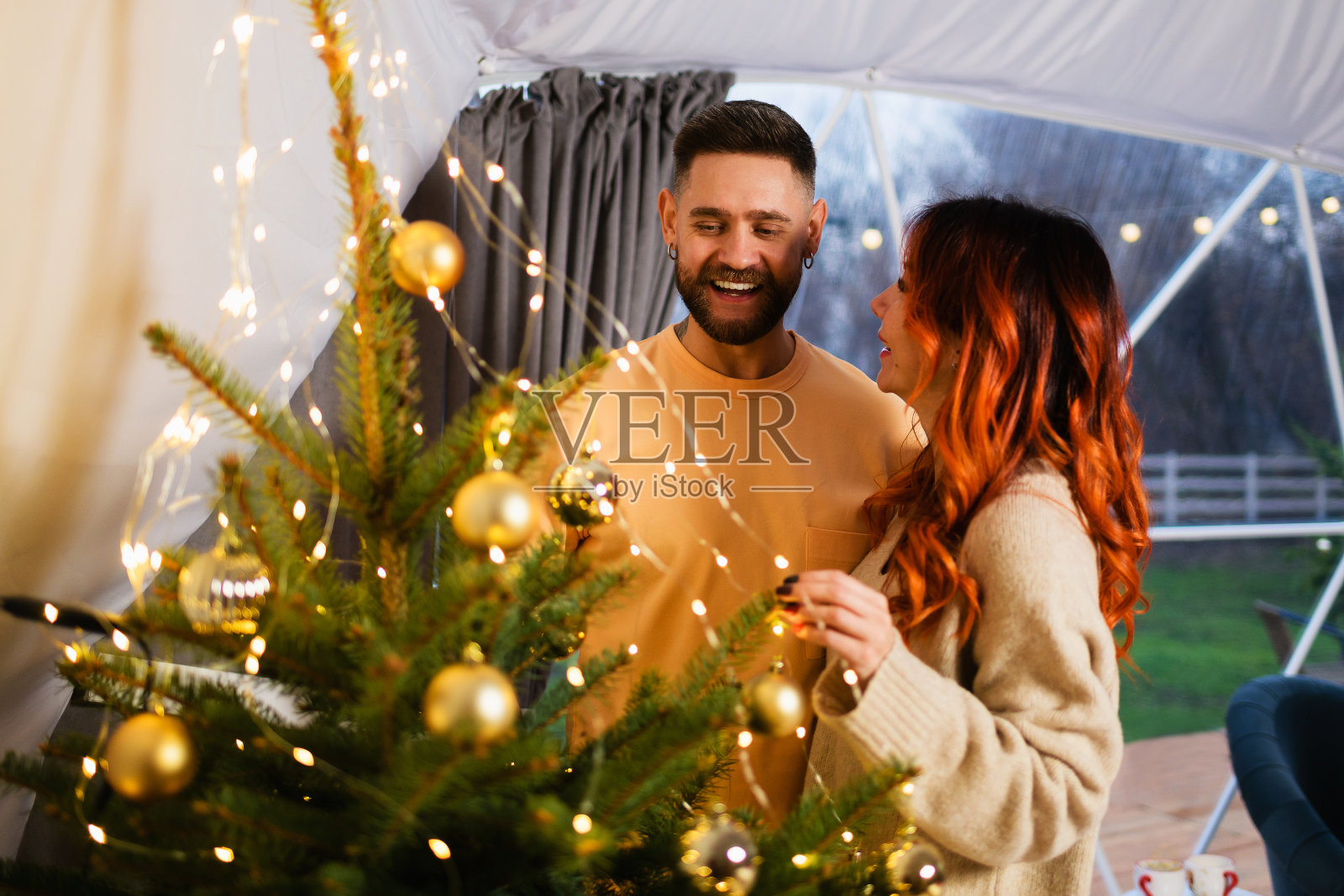 一对情侣在圣诞树旁互相微笑照片摄影图片