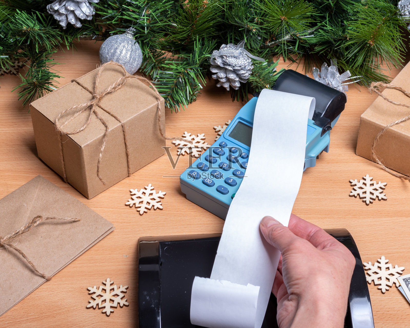 手里拿着一张空白长的收银机收据，从收银机柜台上拿着礼品盒，云杉照片摄影图片