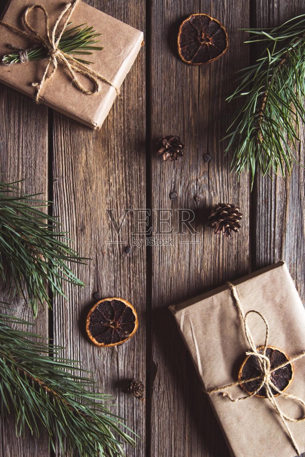 圣诞礼物为新年用牛皮纸包裹在树枝和木制背景锥附近照片摄影图片