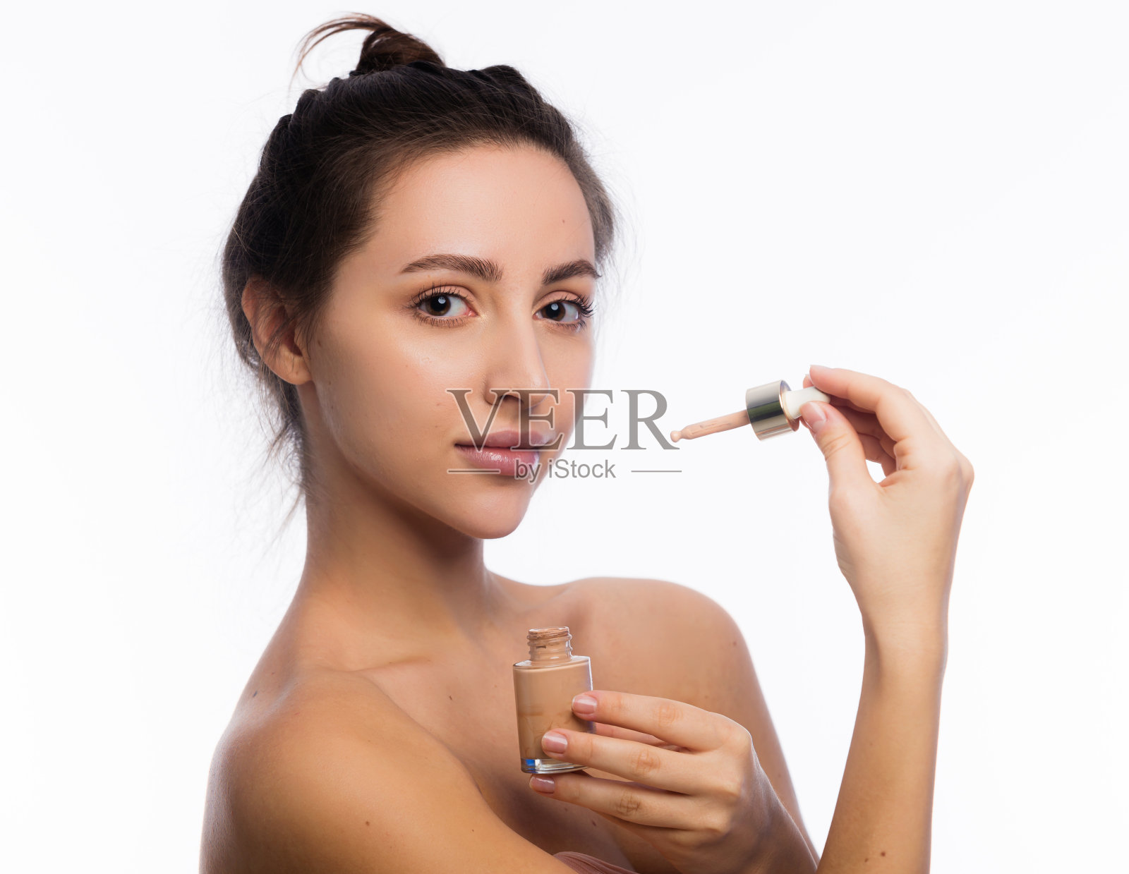 美丽优雅的年轻女子欣然持有粉底或护肤品。有吸引力的女人和护肤品看着相机。隔离在空白复制空间照片摄影图片