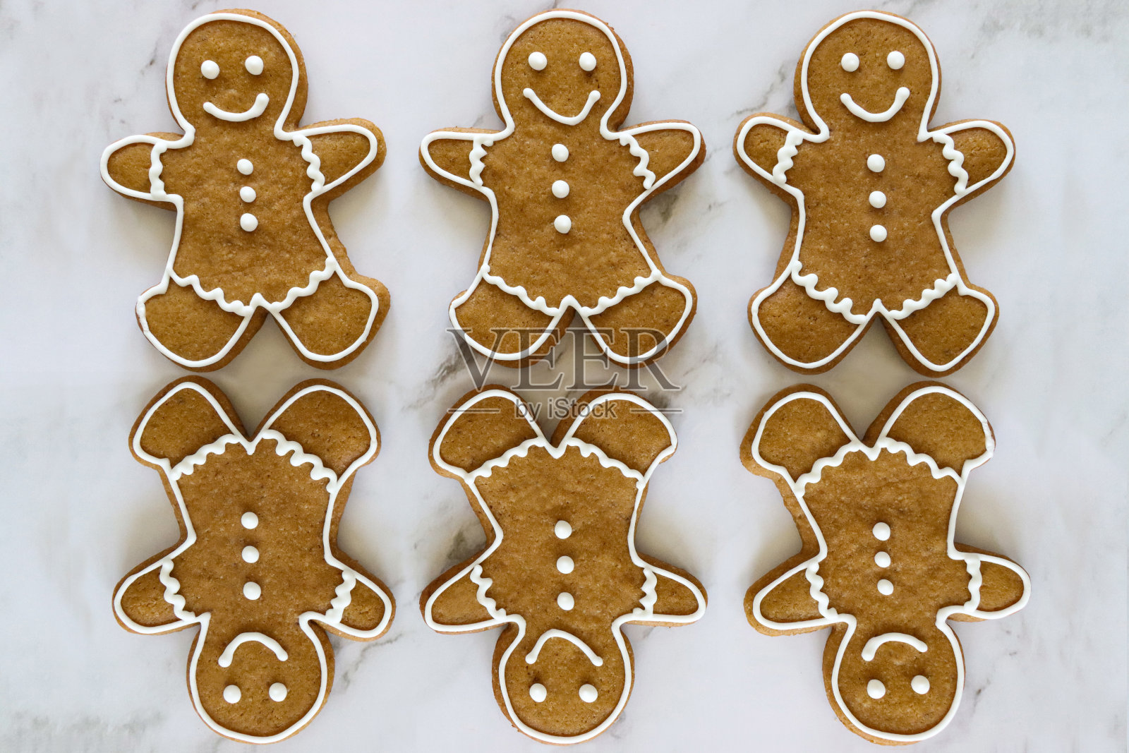 成排的自制姜饼人饼干，糖衣白色，皇家糖衣大理石效果背景，六块饼干，三块倒置的饼干，升高的视野照片摄影图片
