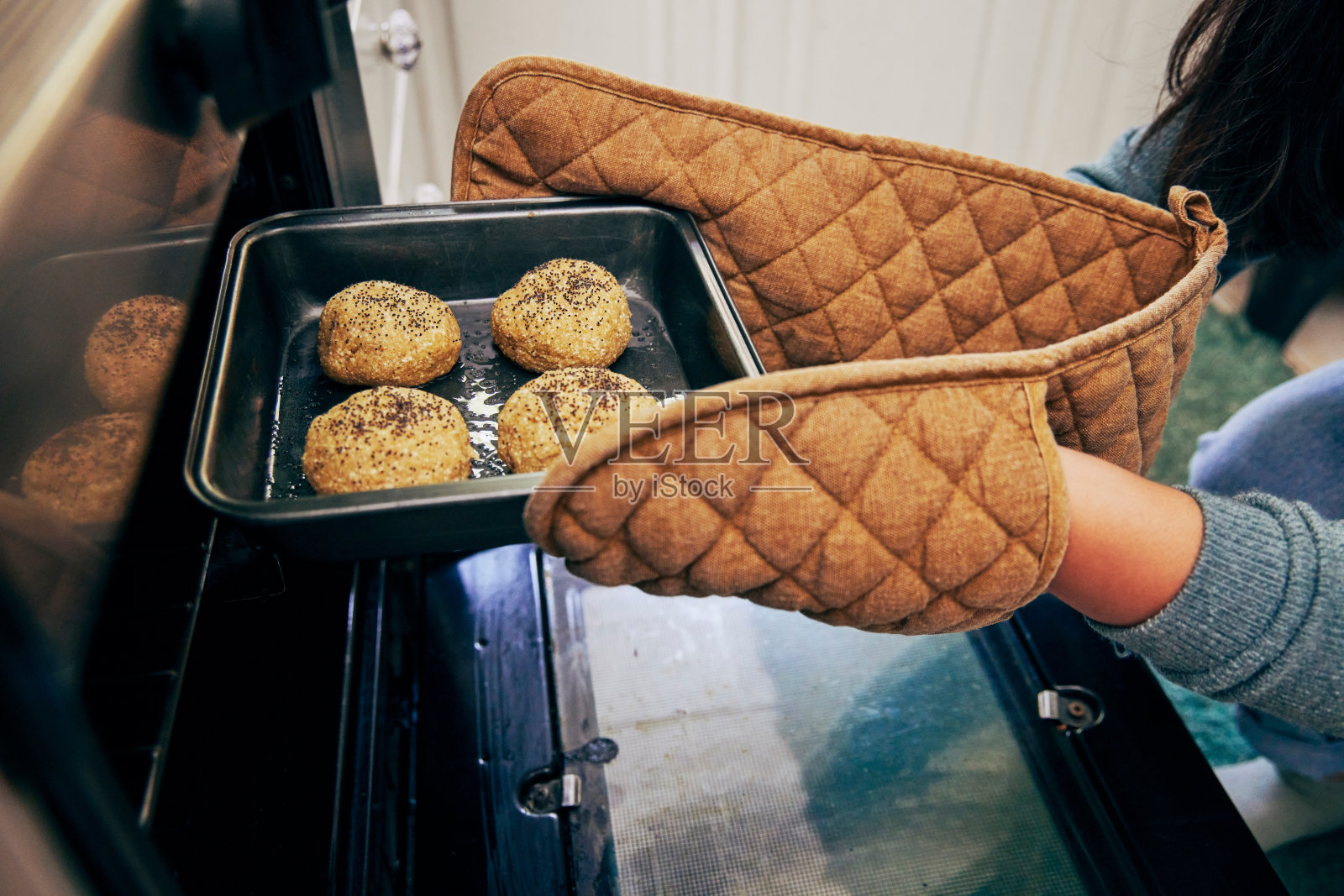 一个女人把一盘面包放进烤箱烤照片摄影图片