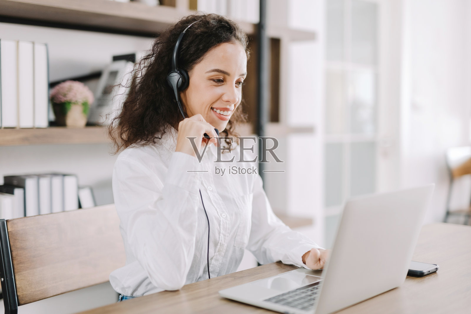 一个年轻的女商人用她的智能手机的相机在开心地自拍，给她的朋友们看在工作，放松，在办公室休息。照片摄影图片