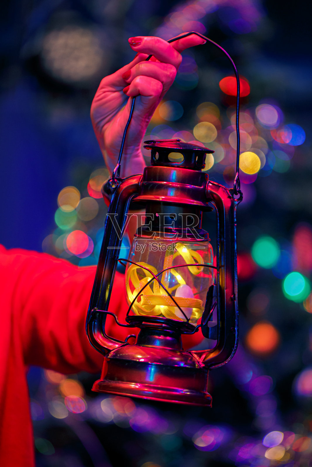 圣诞之夜，一只手拿着一个旧煤油灯。明亮模糊美丽的背景与彩色散景。软焦点照片摄影图片