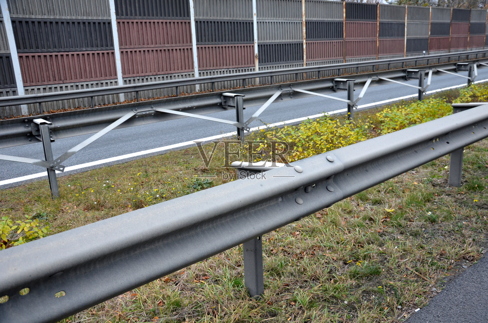 用螺钉连接金属和混凝土公路屏障。在车道之间没有足够空间的地方，用金属支柱和拉紧钢筋进行加固。隔音屏障照片摄影图片