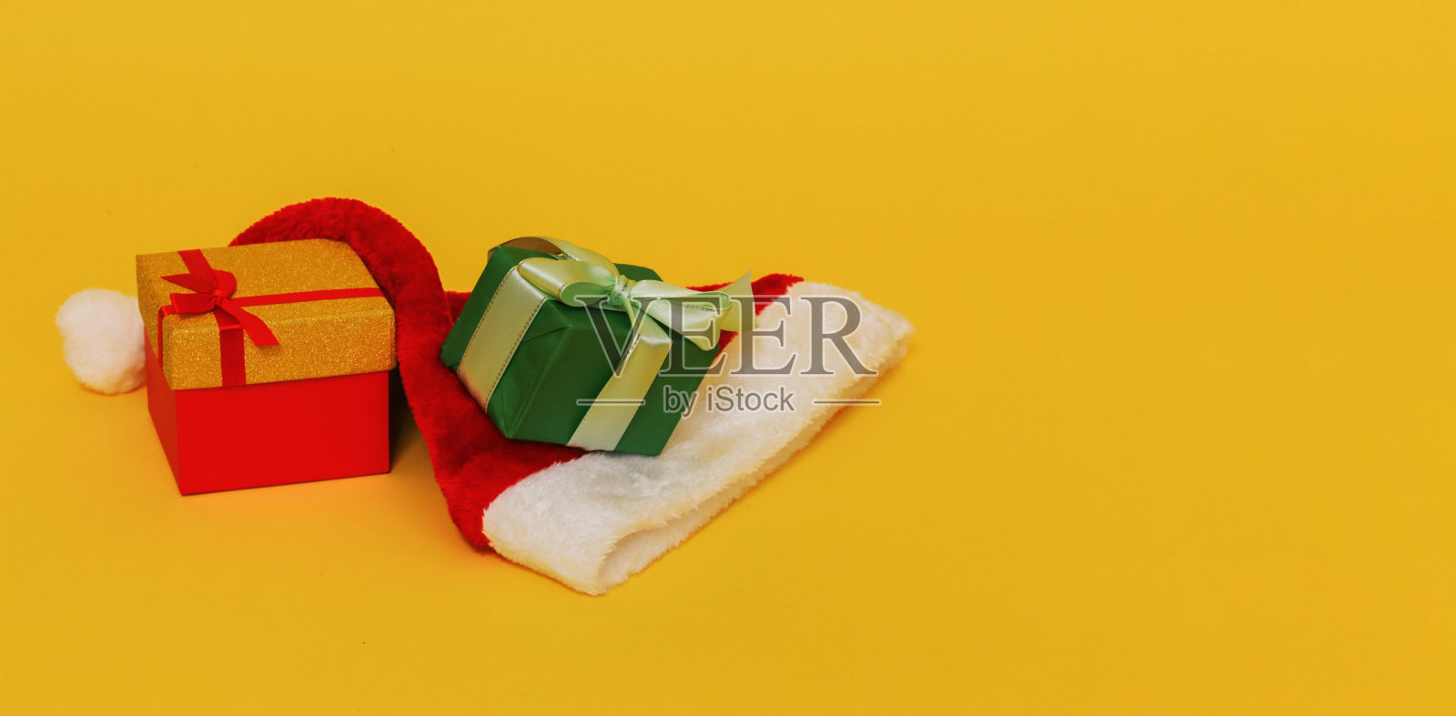 两个盒子里的礼物和一顶圣诞老人的帽子。照片摄影图片