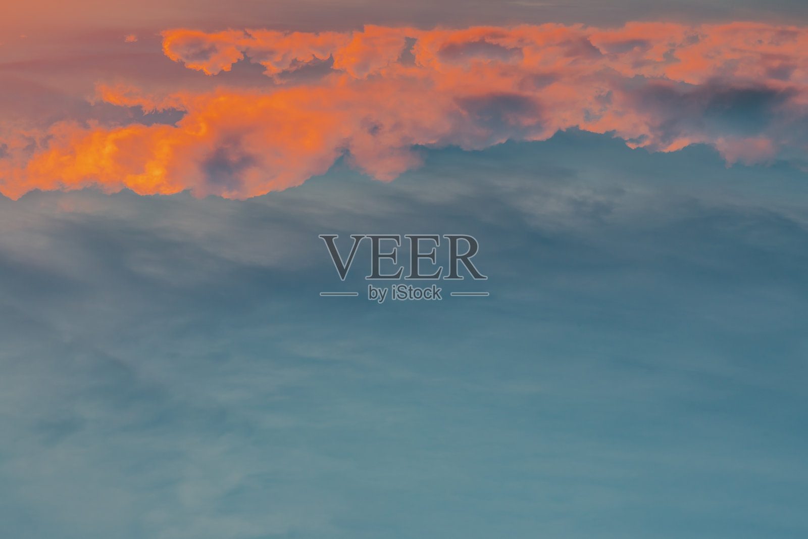 夕阳的天空中，太阳透过云层，发出戏剧性的光芒。云的形状唤起想象力和创造力。照片摄影图片