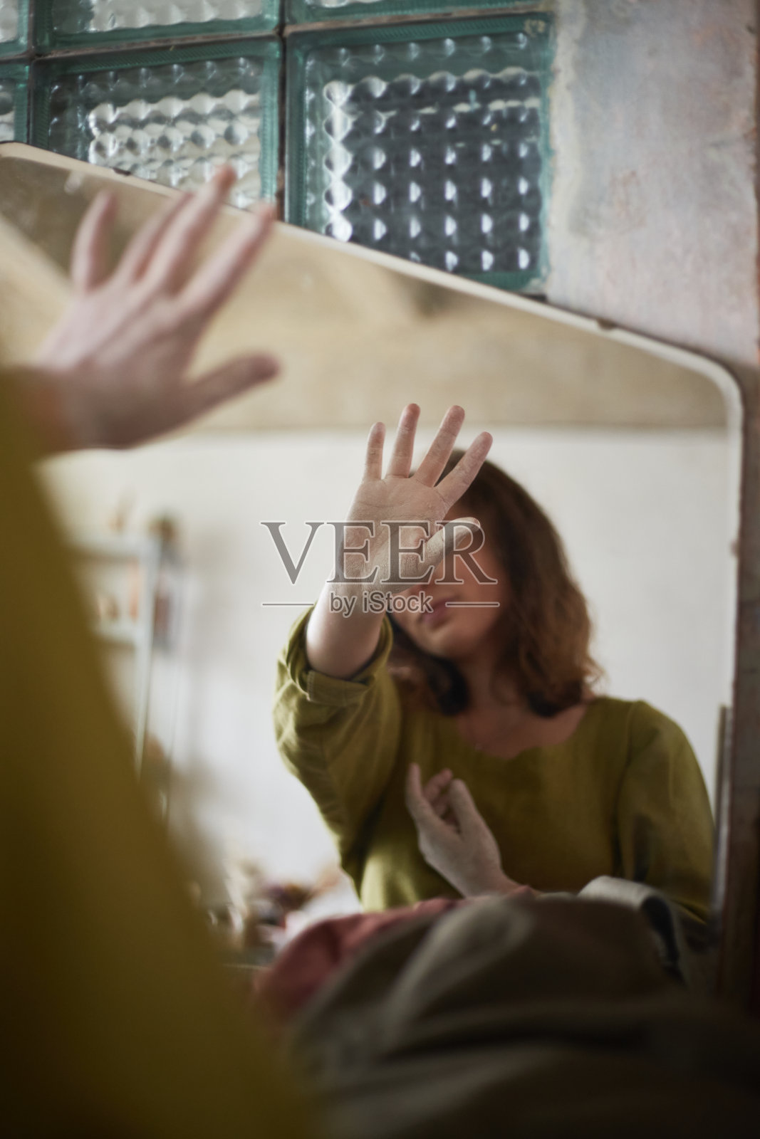 近距离肖像的陶艺家和她的手脏粘土在镜子。陶艺工作室制作陶器的过程。这位陶艺家大师在她的画室里工作照片摄影图片