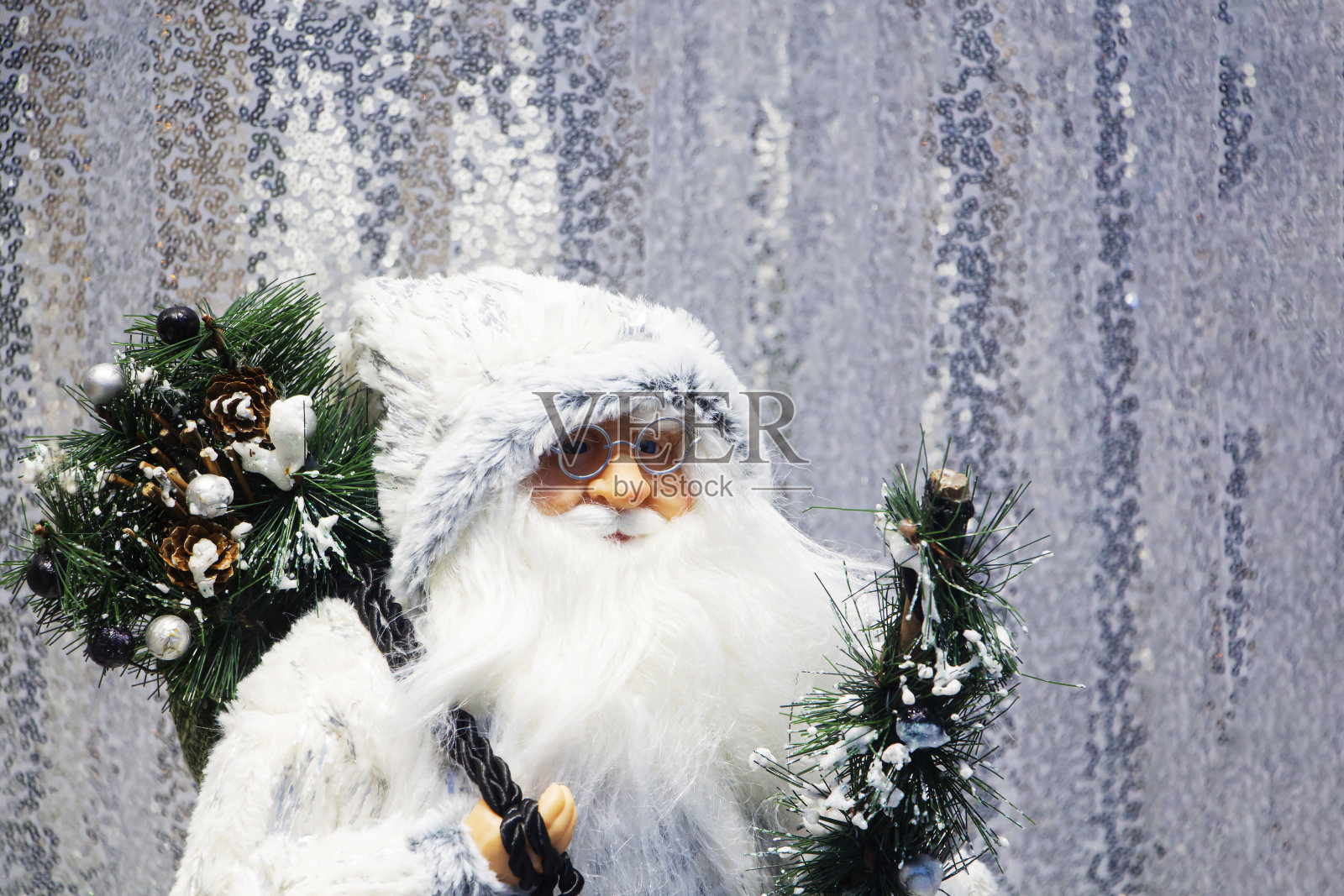 一个戴着眼镜和白胡子的圣诞老人娃娃和一棵圣诞树。照片摄影图片