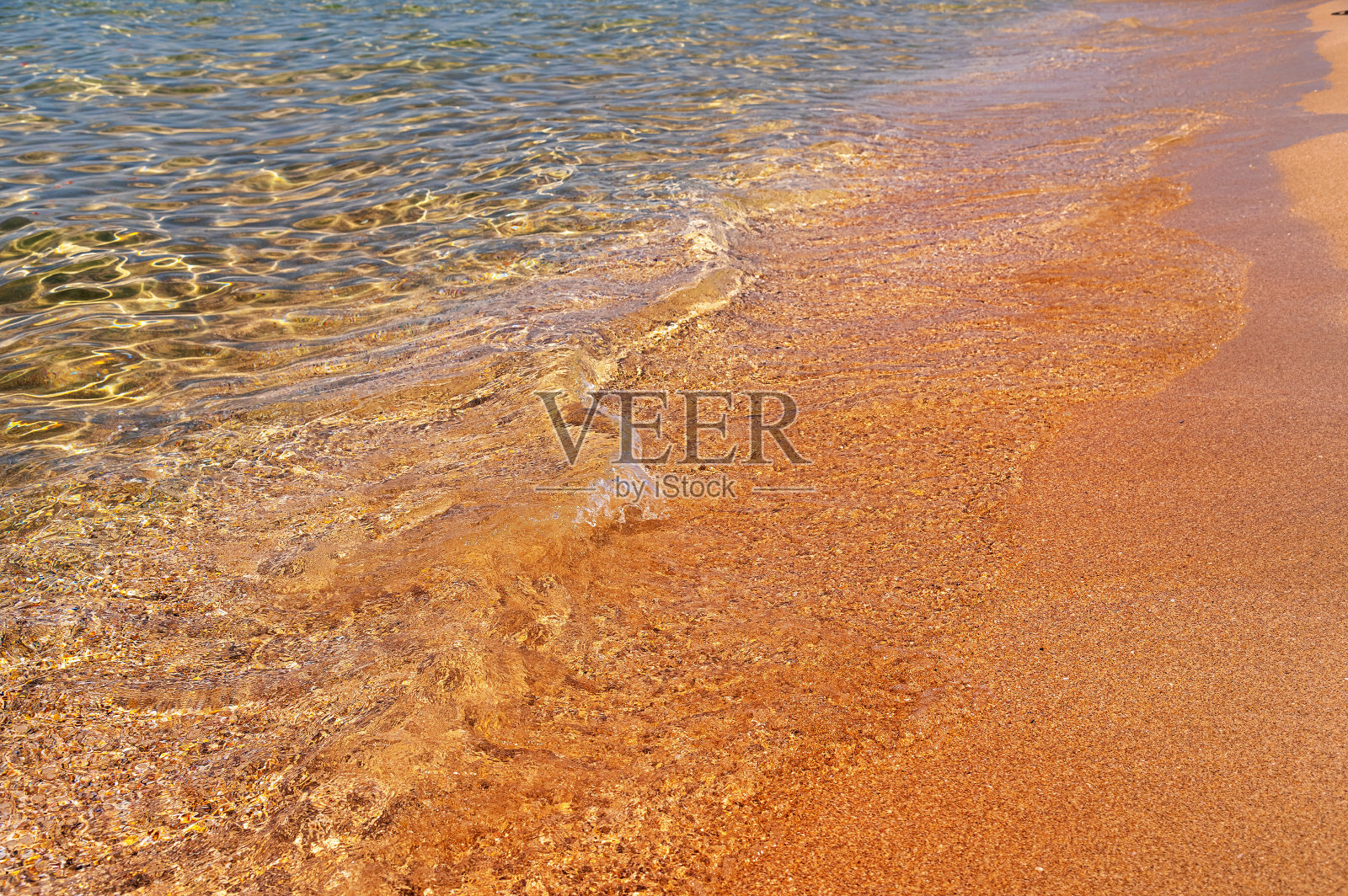 透明的海水。金色的沙滩被带着泡沫的小浪花冲刷着。海洋背景。旅游和旅行照片摄影图片