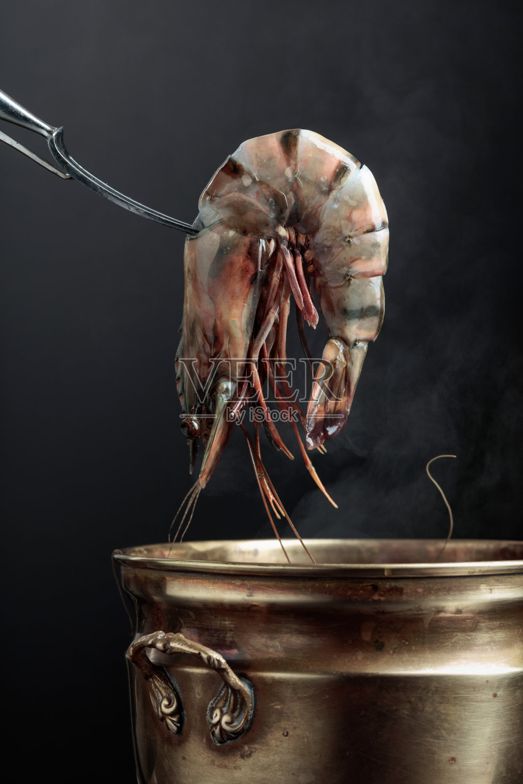 虎虾被放在一个旧铜锅里。照片摄影图片