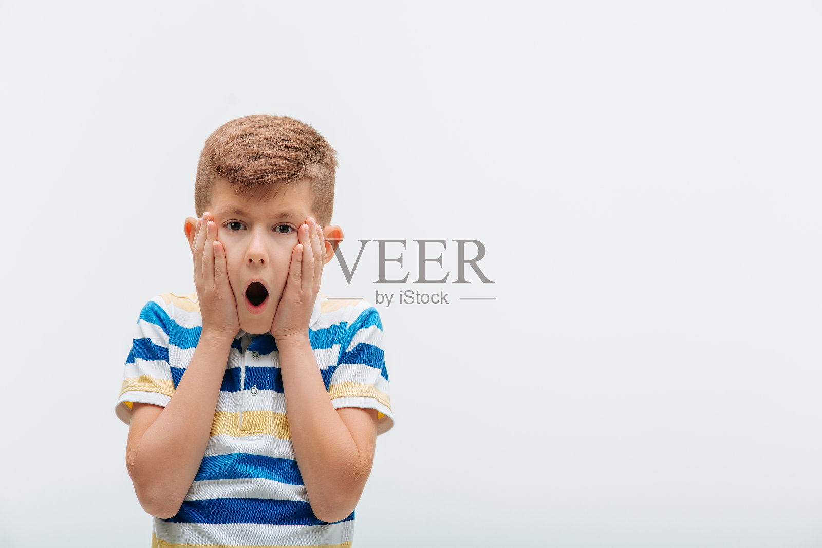 近距离拍摄的小男孩惊讶地看着相机，表情震惊，照片摄影图片