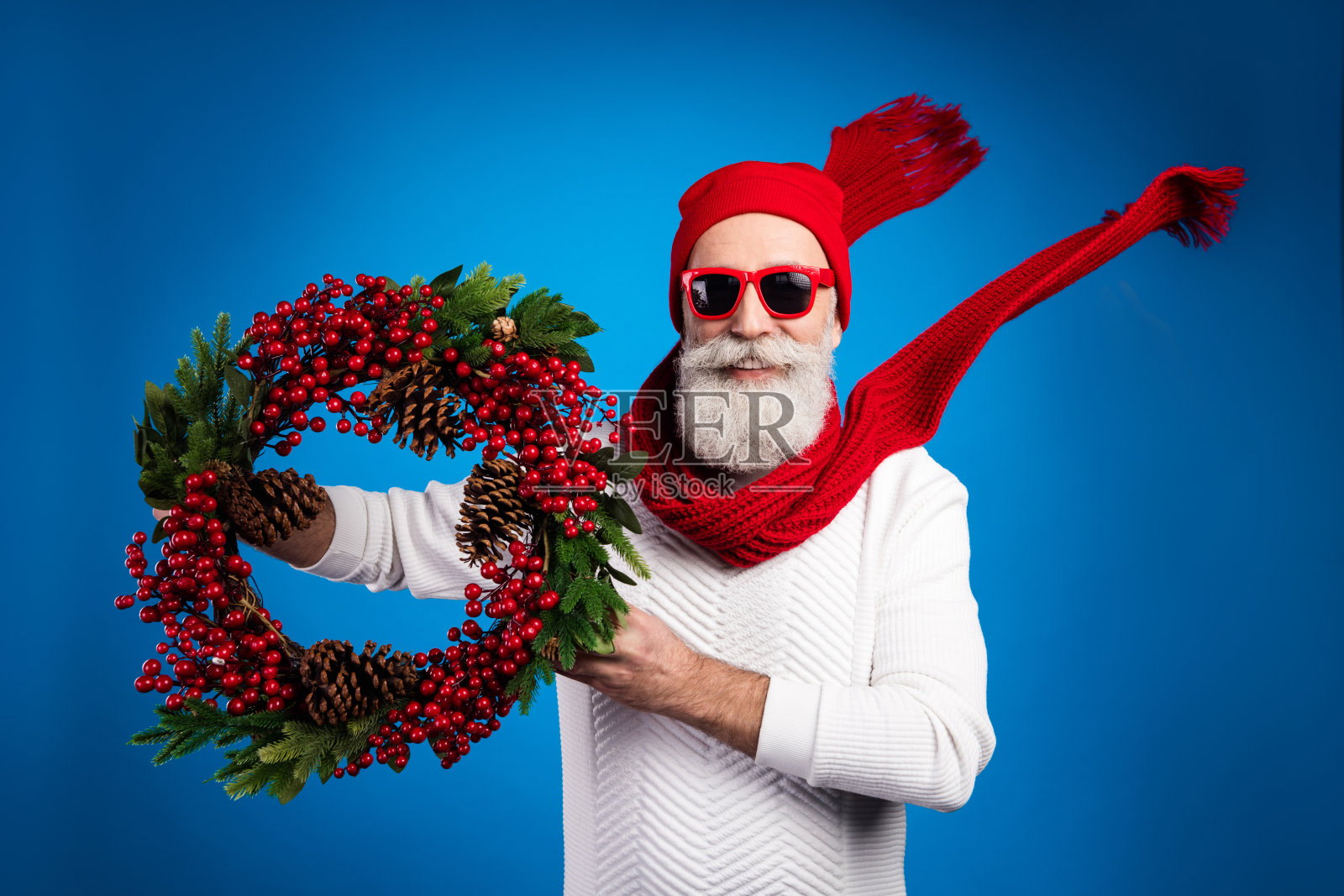 照片相当迷人的成熟男子穿着白色套衫红色头饰持圣诞花环孤立的蓝色背景照片摄影图片