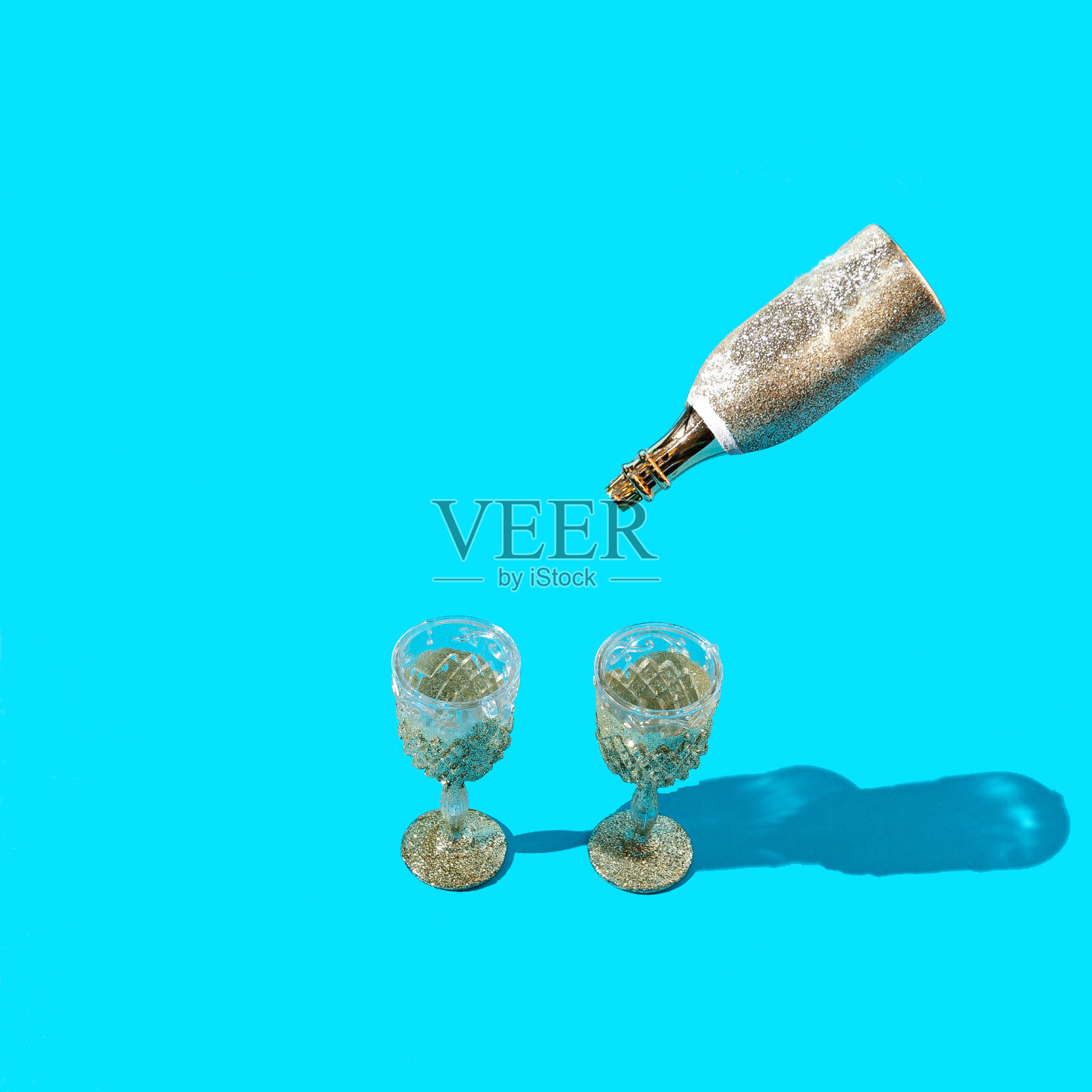 两个带有金箔的香槟杯和一瓶香槟从上面倒酒照片摄影图片