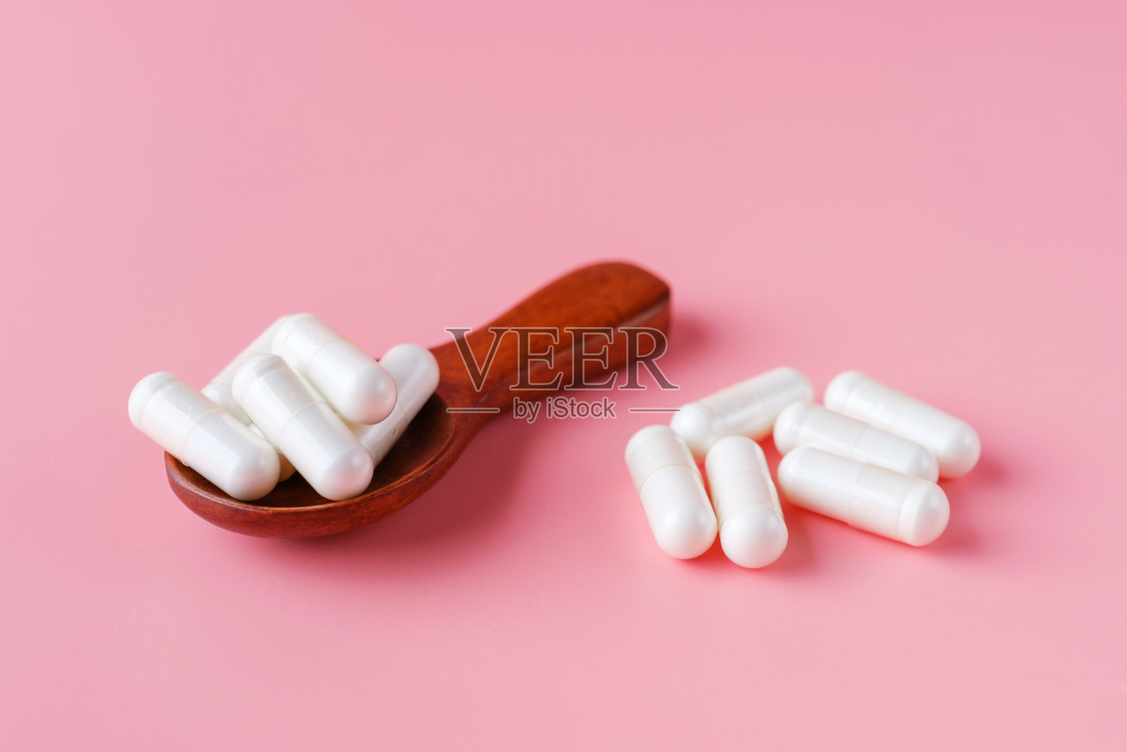 粉红色背景下的胶原蛋白胶囊(正面)。照片摄影图片