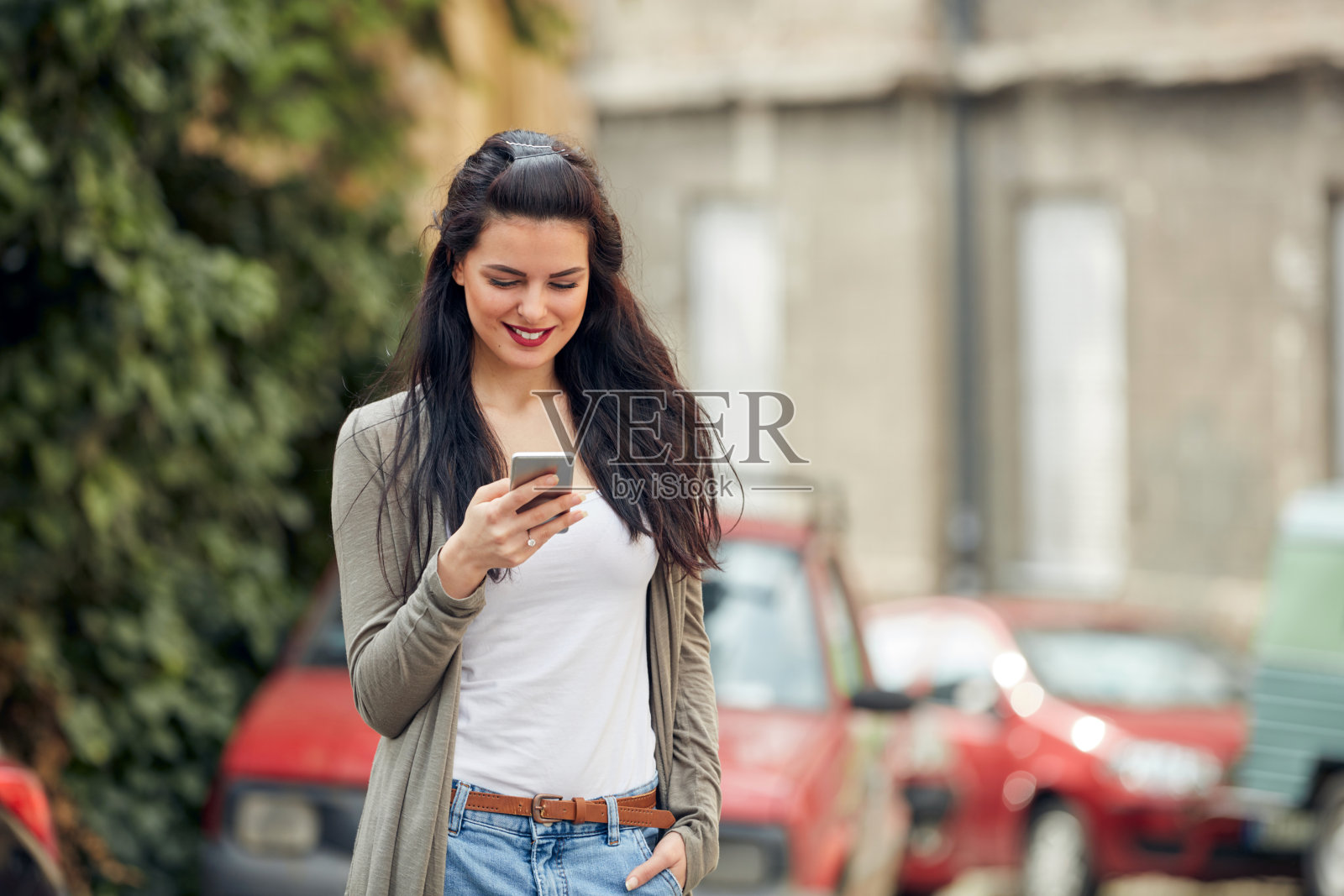 年轻可爱的女性在街上使用智能手机。照片摄影图片