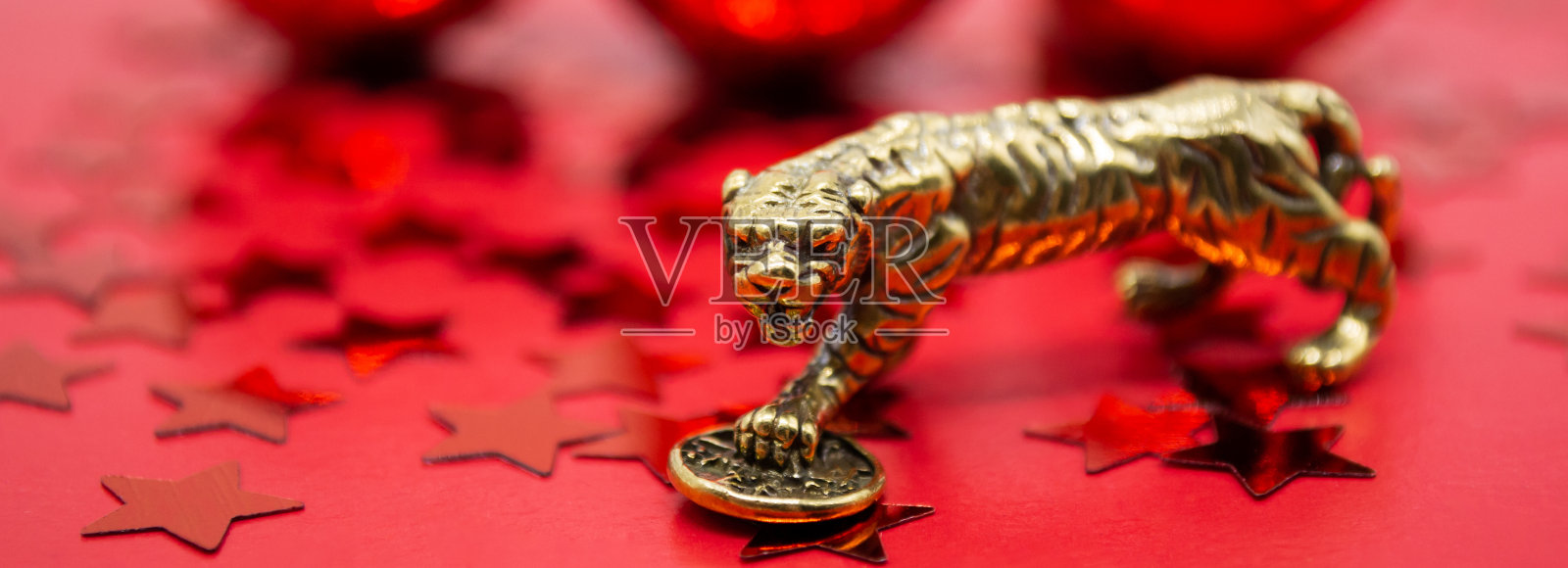 以红星和红球为背景的旗帜上的铜像老虎和硬币- 2022年中国新年的象征，一个复制空间照片摄影图片