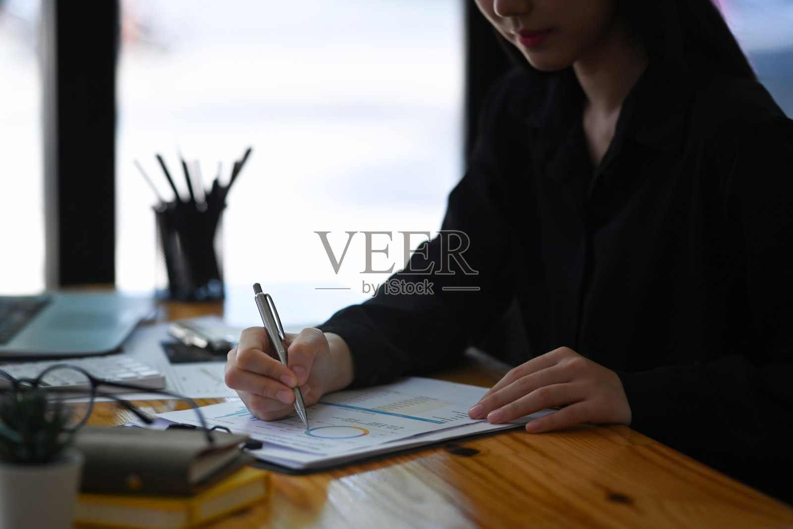 裁剪的女会计正在办公室的办公桌上签字。照片摄影图片