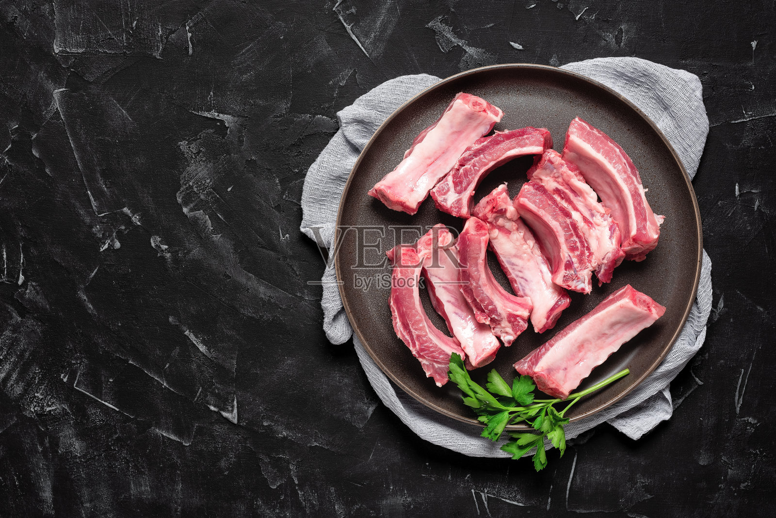 一盘生排骨，背景为黑色石头。俯视图，平铺。照片摄影图片