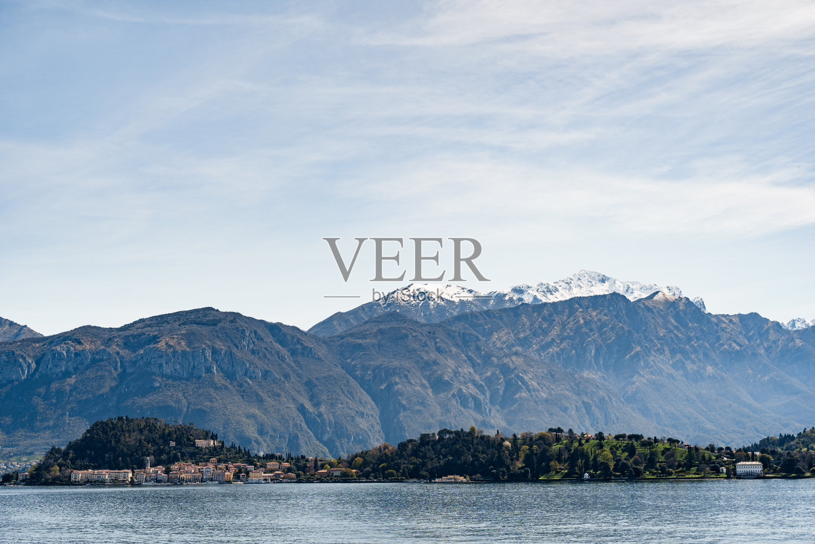 从科莫湖(Lake Como)到山脉背景下的海岸房屋。百乐宫,意大利照片摄影图片