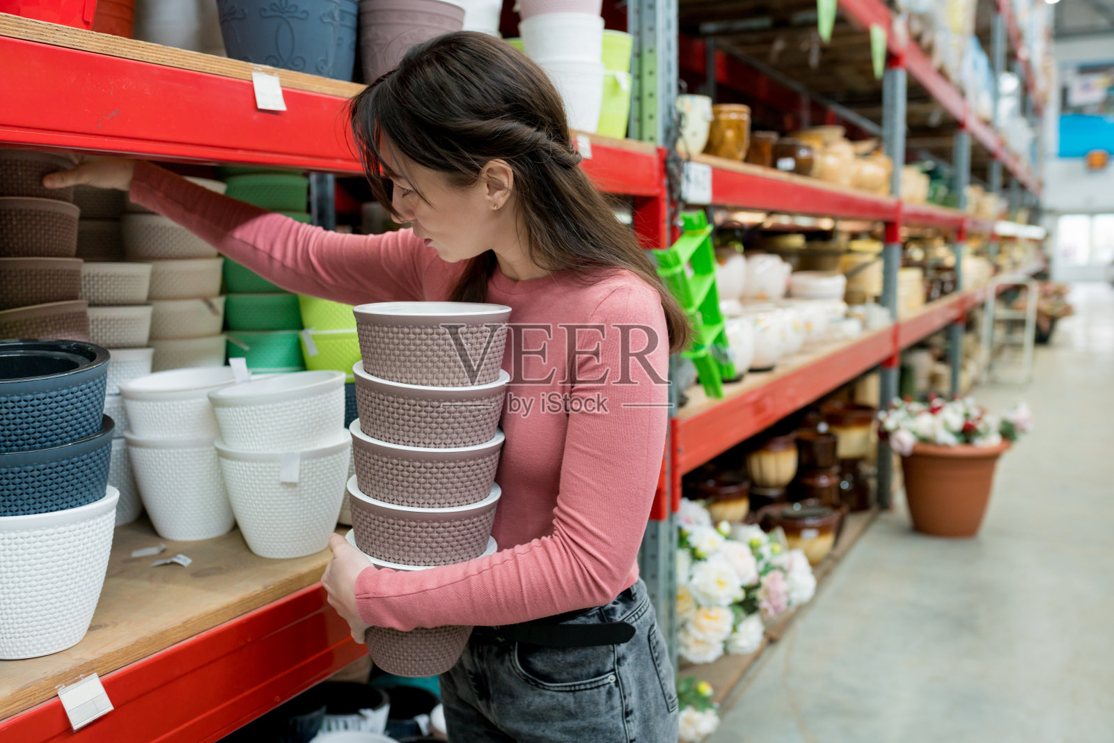 漂亮的女人在花园中心选择陶瓷花盆作为室内植物。女性在自家仓库买了一个插秧机来插秧照片摄影图片