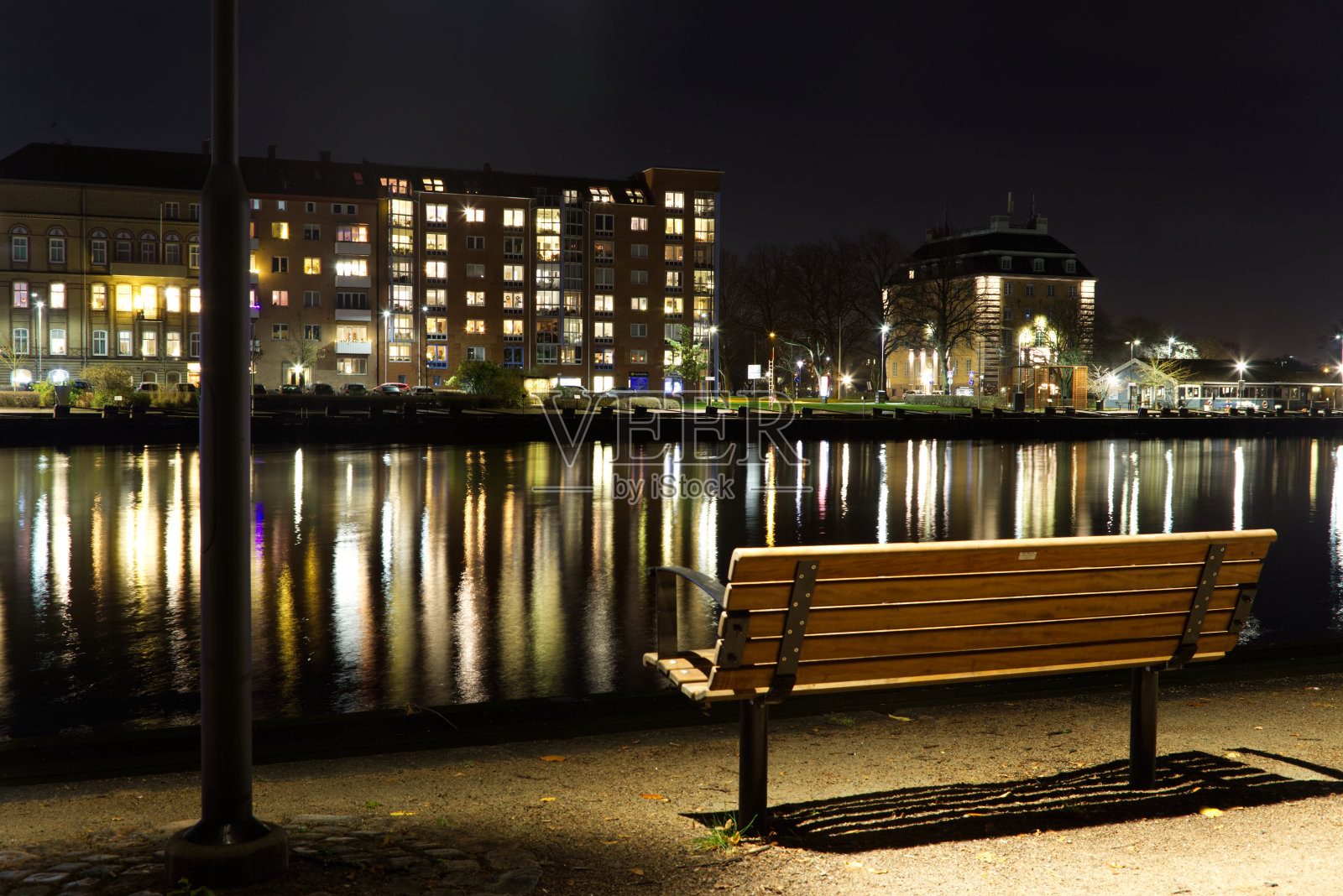 在哈尔姆斯塔德，公园的长椅面朝河流，倒影在水面上。照片摄影图片