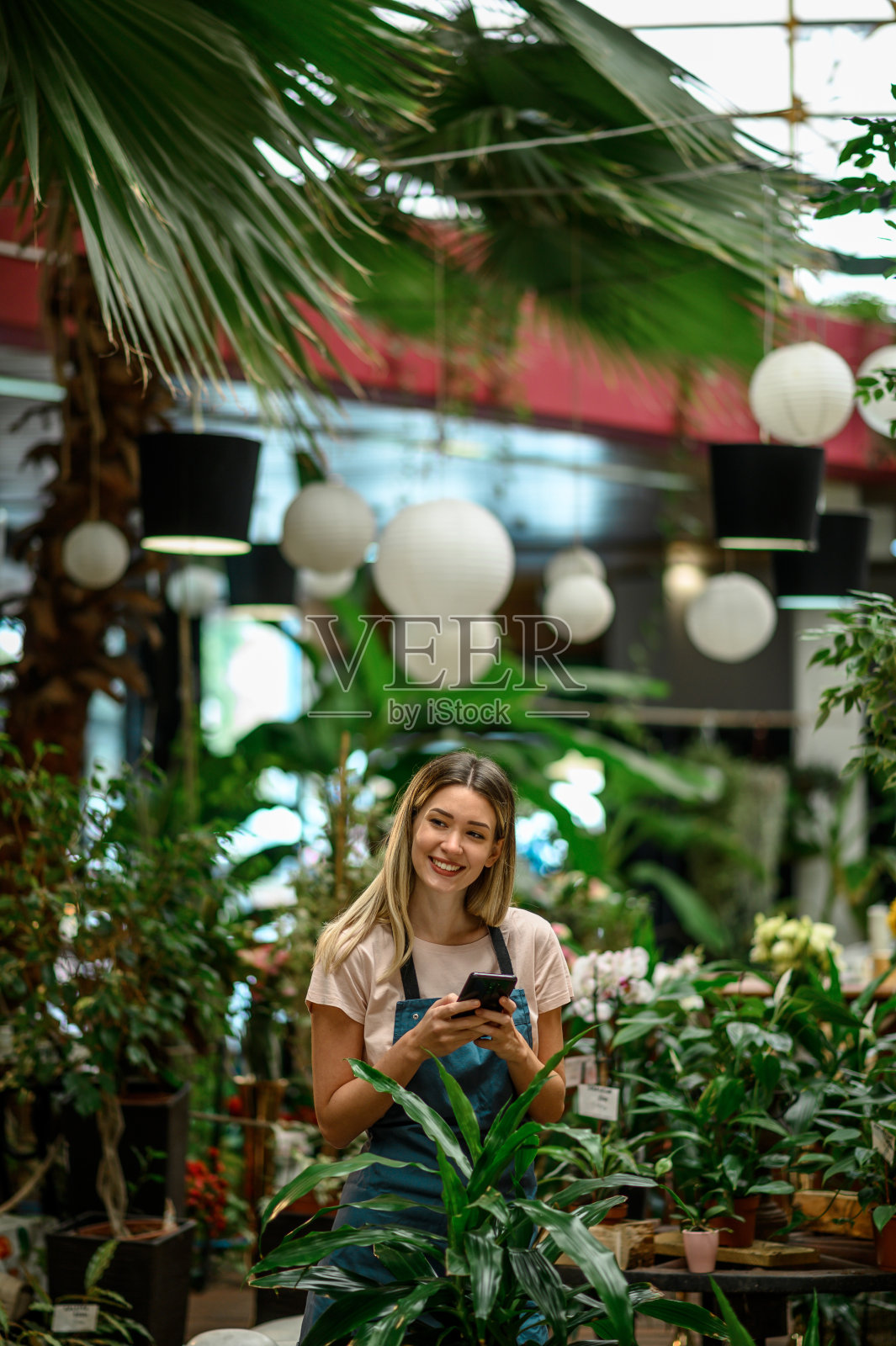花商一边照顾植物一边用智能手机照片摄影图片