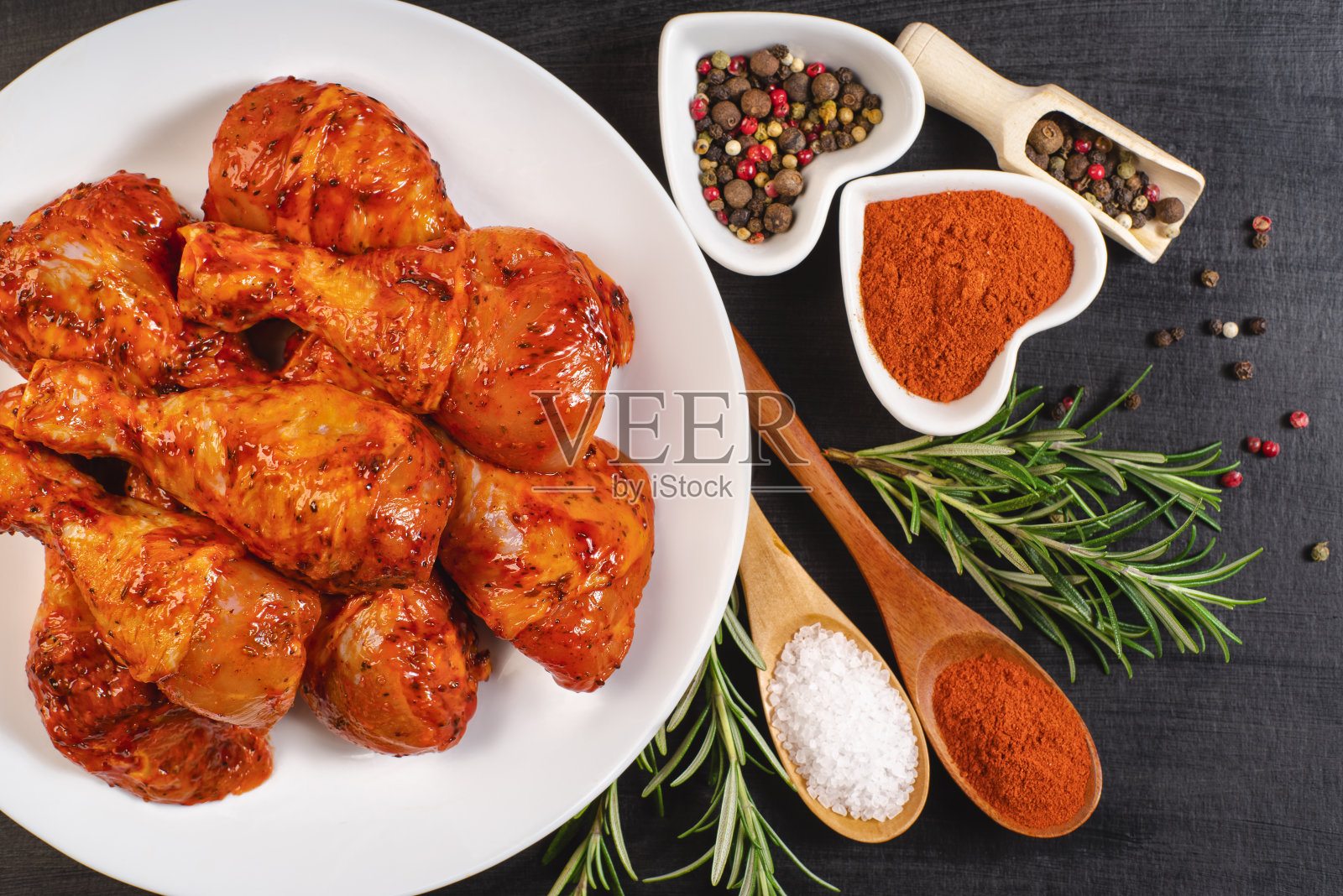 烹饪鸡腿。用迷迭香和胡椒腌制的生鸡腿。前视图。热的烤鸡腿。生鸡腿。美味的腌鸡腿。照片摄影图片