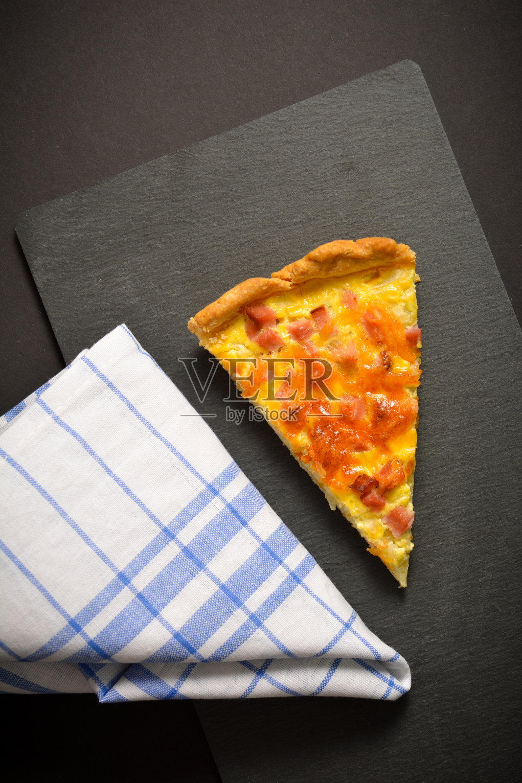 俯视图一块馅饼与鸡蛋和培根在石头盘与纺织厨房毛巾在黑色的背景照片摄影图片