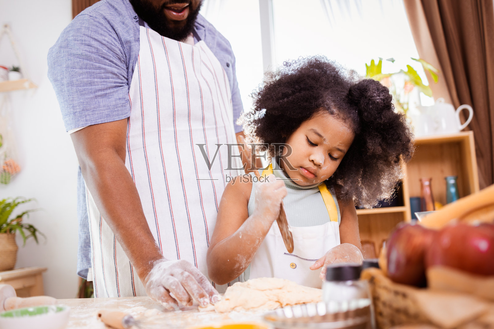 快乐的非裔美国父亲和女儿在家里准备饼干面团的乐趣。幸福的家庭时间。照片摄影图片