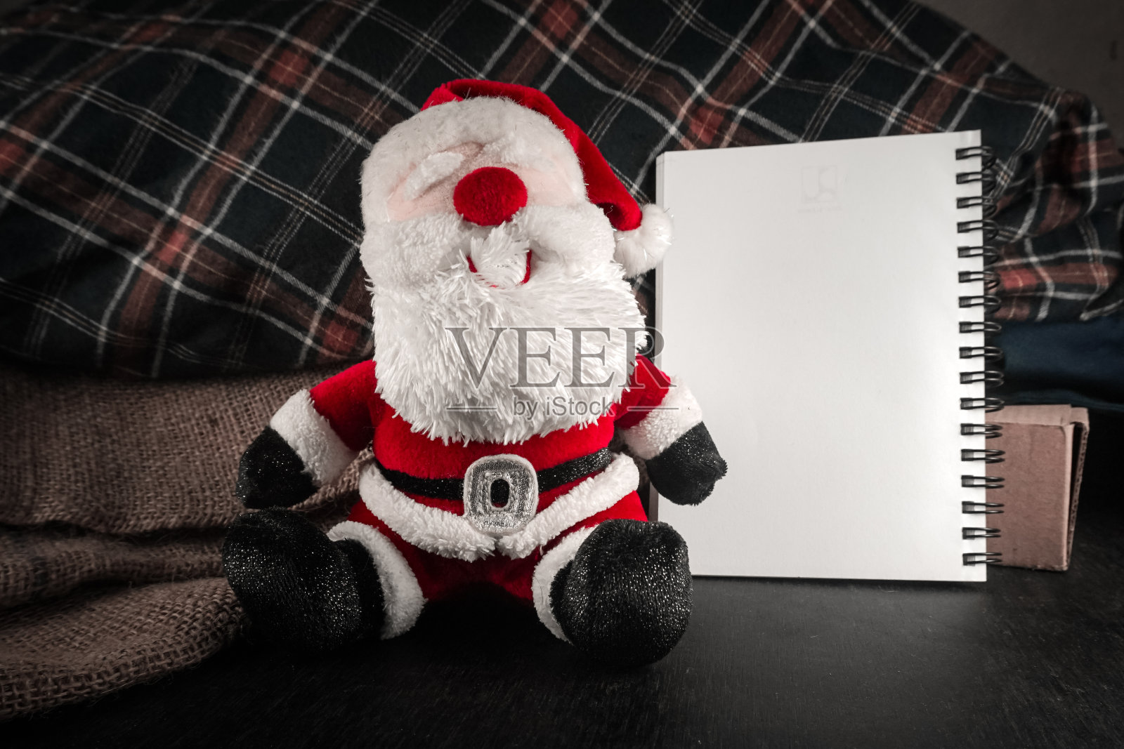 圣诞老人玩偶坐在装订书旁为文本照片摄影图片