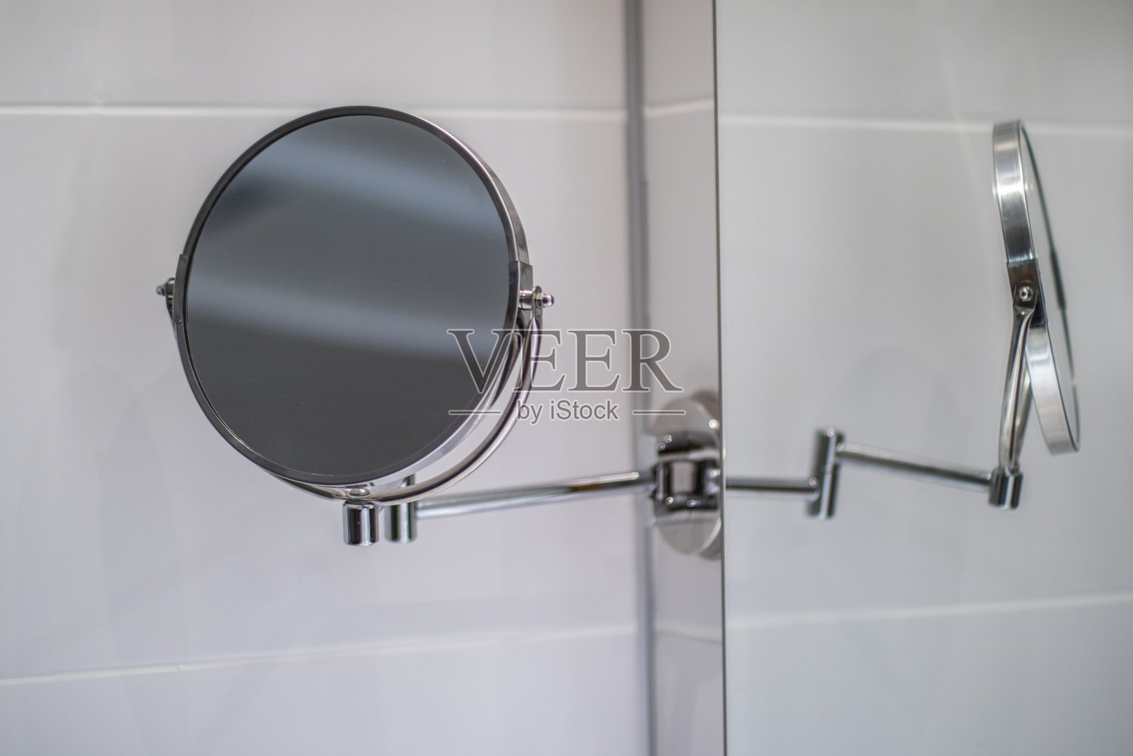 挂在酒店浴室白色镜面墙上的化妆镜照片摄影图片