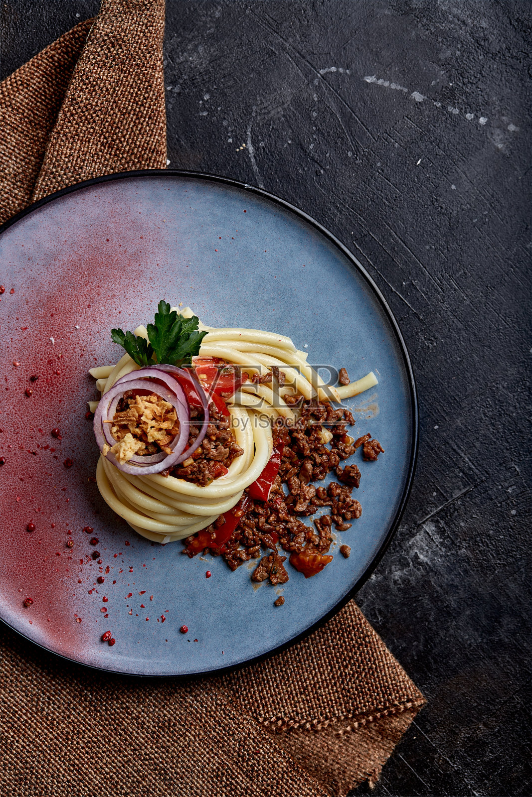 意大利番茄牛肉面。概念意大利菜，漂亮的意大利面放在盘子里，浇上肉酱。蓝色车牌，深色背景。俯视图照片摄影图片