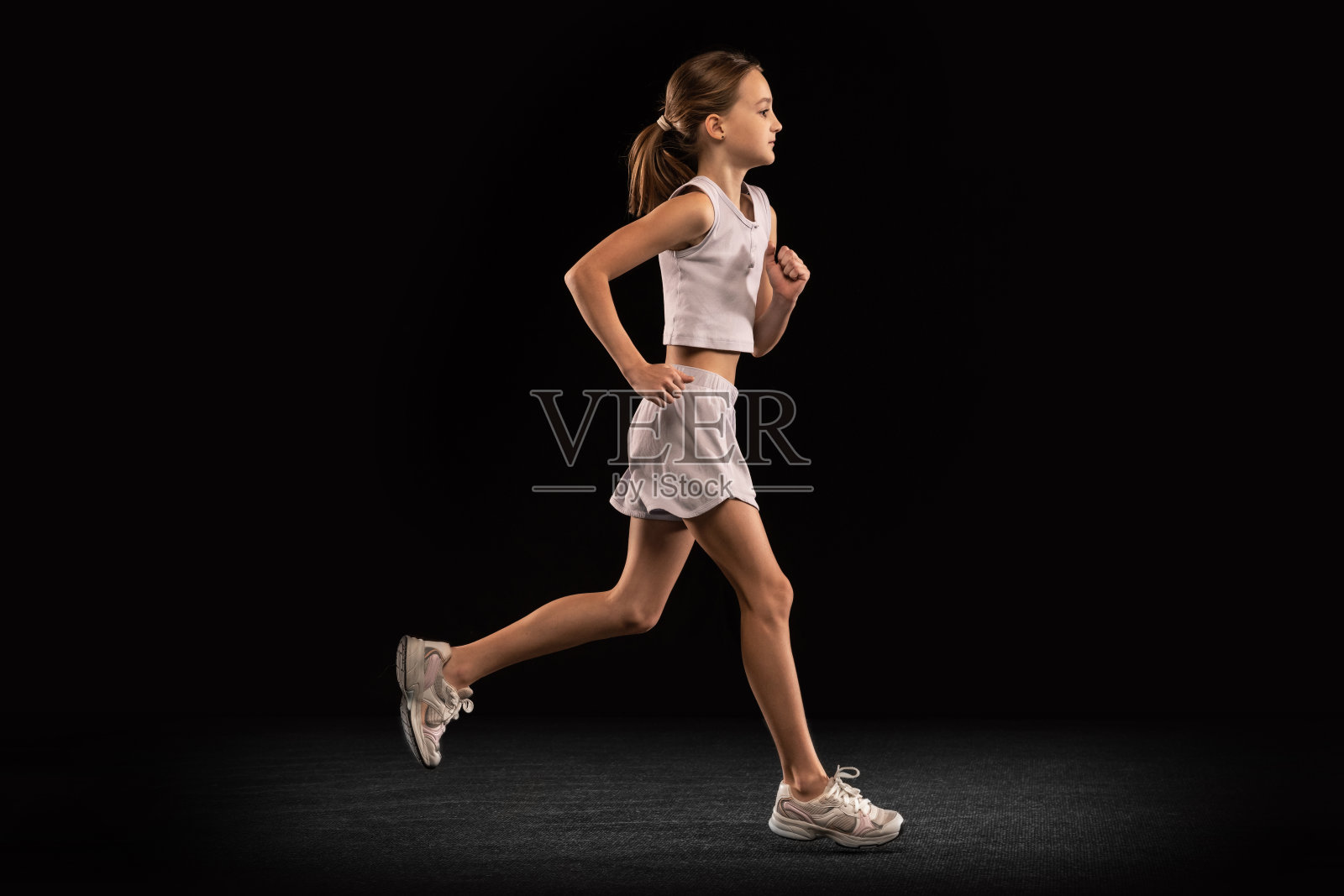 全身肖像的女孩，青少年，运动员训练跑步孤立的黑色背景。侧视图照片摄影图片