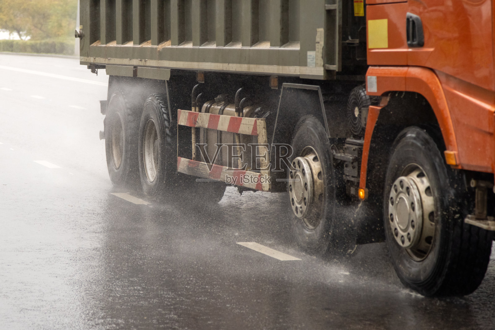 在潮湿的路面上行驶的重型卡车在白天溅起水花照片摄影图片