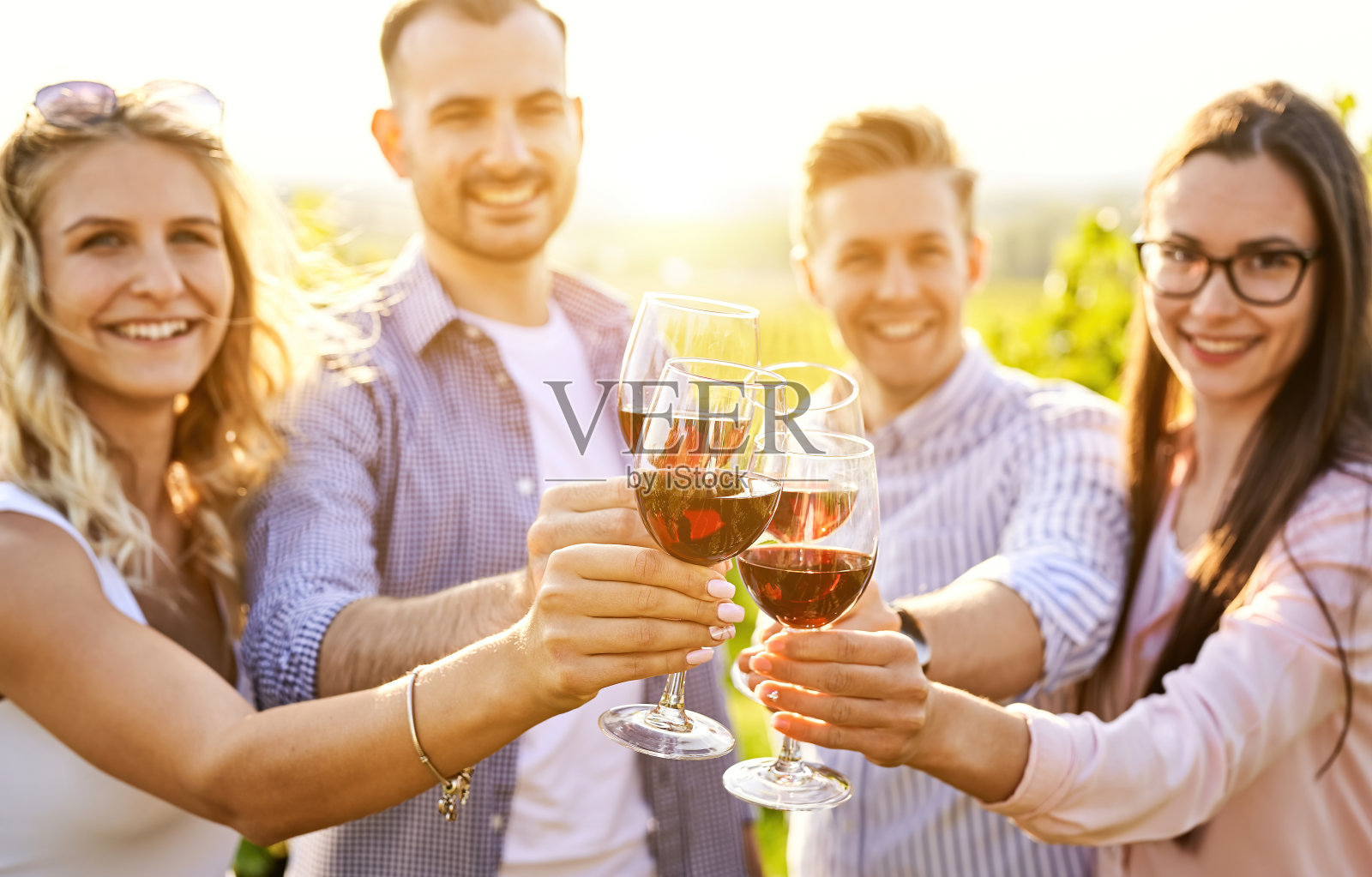 年轻的朋友们在户外玩耍-快乐的人们在农家酒庄乡村一起享受丰收的时光-青春和友谊的概念-日落前在葡萄园敬酒照片摄影图片