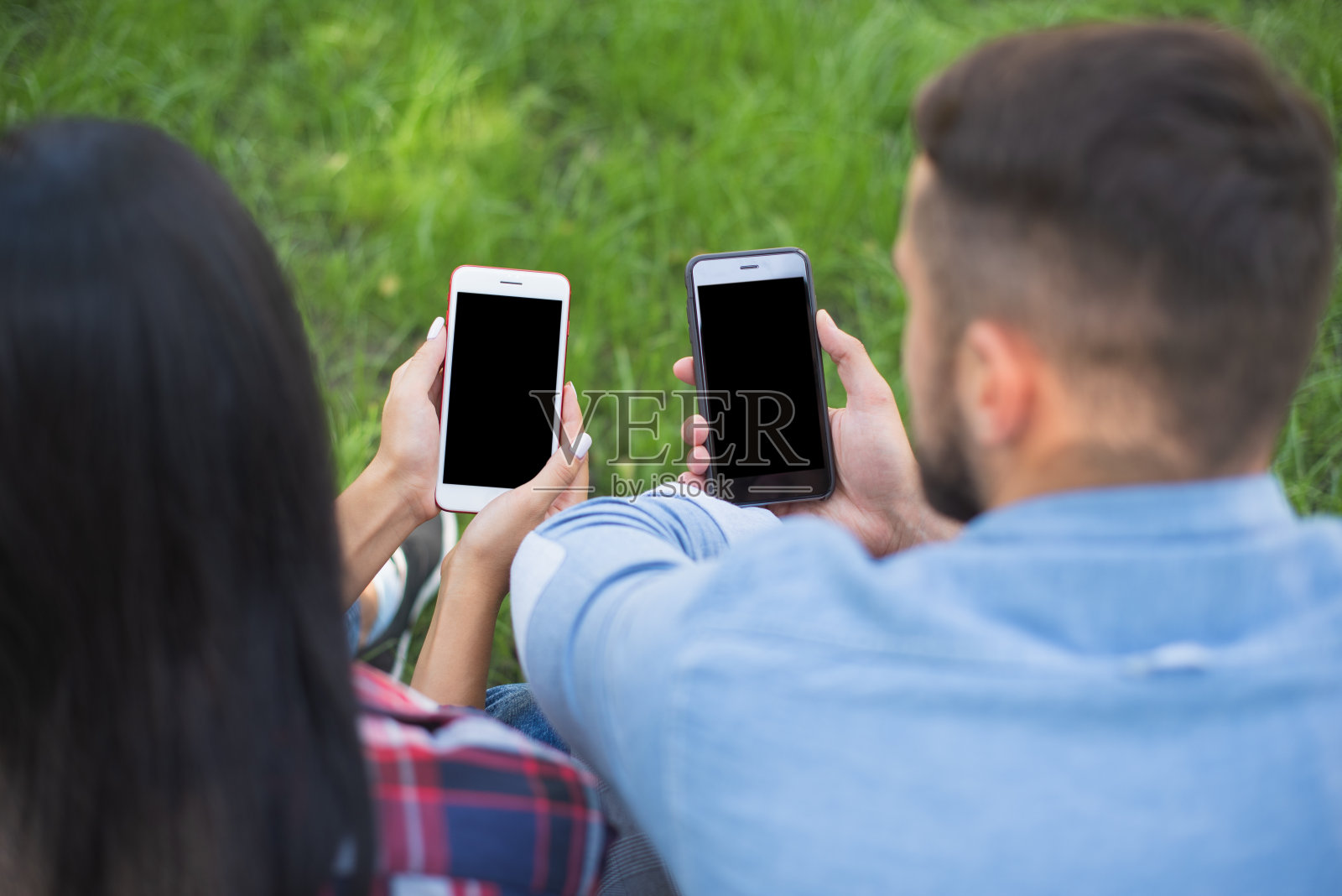 迷恋的男孩和女孩看着智能手机。社交媒体上瘾。通过社交网络联系人们照片摄影图片