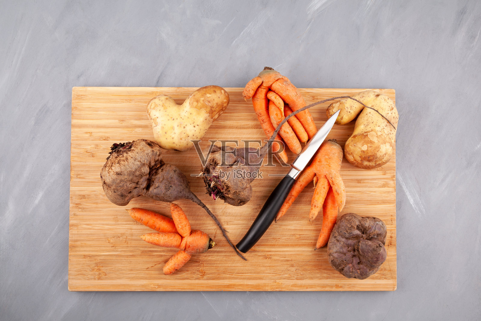 不同丑陋的蔬菜在砧板上，俯视图。概念-减少食物有机废物。用于烹饪不完美的产品照片摄影图片