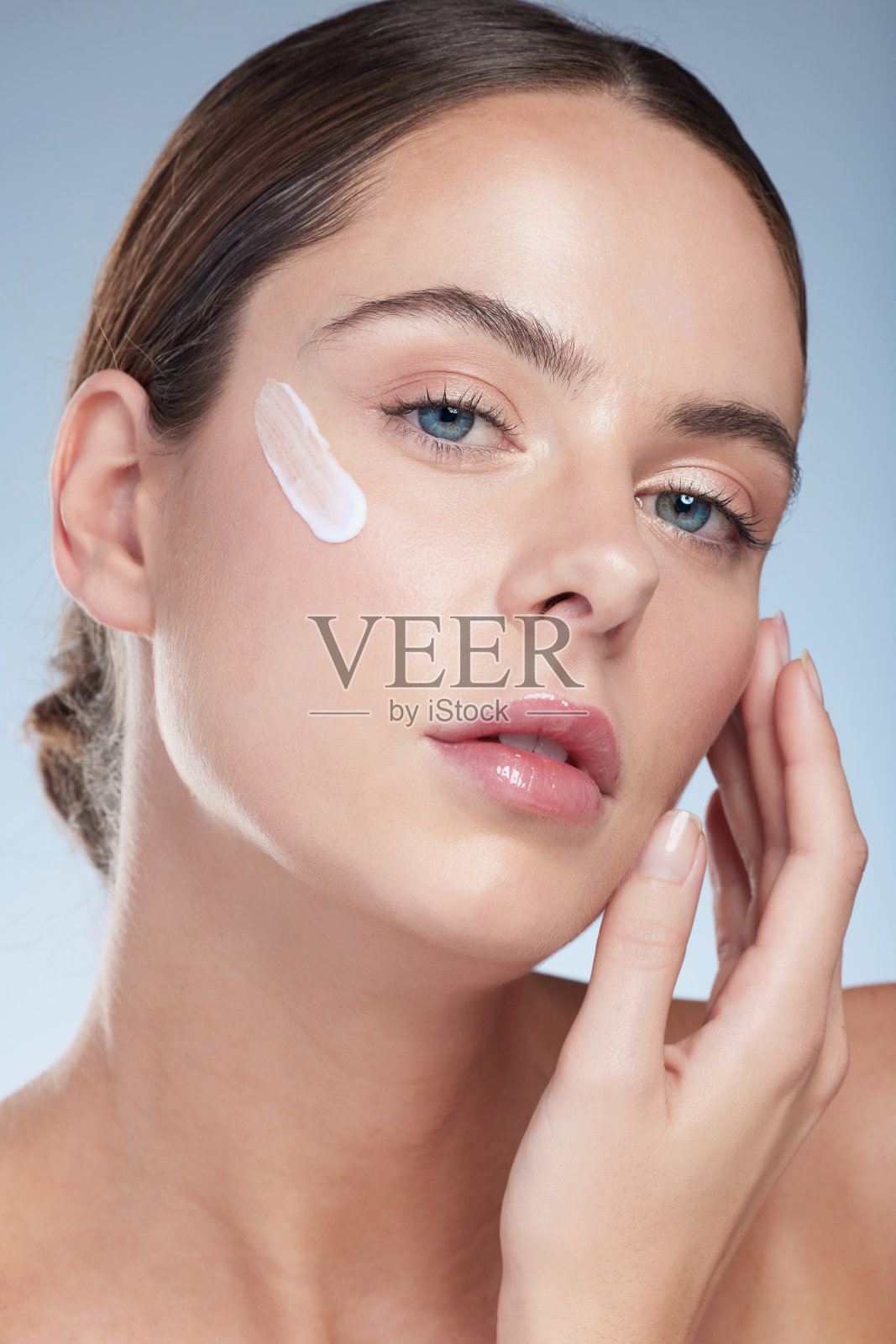 画室肖像，一个迷人的年轻女子滋润她的脸在灰色的背景照片摄影图片