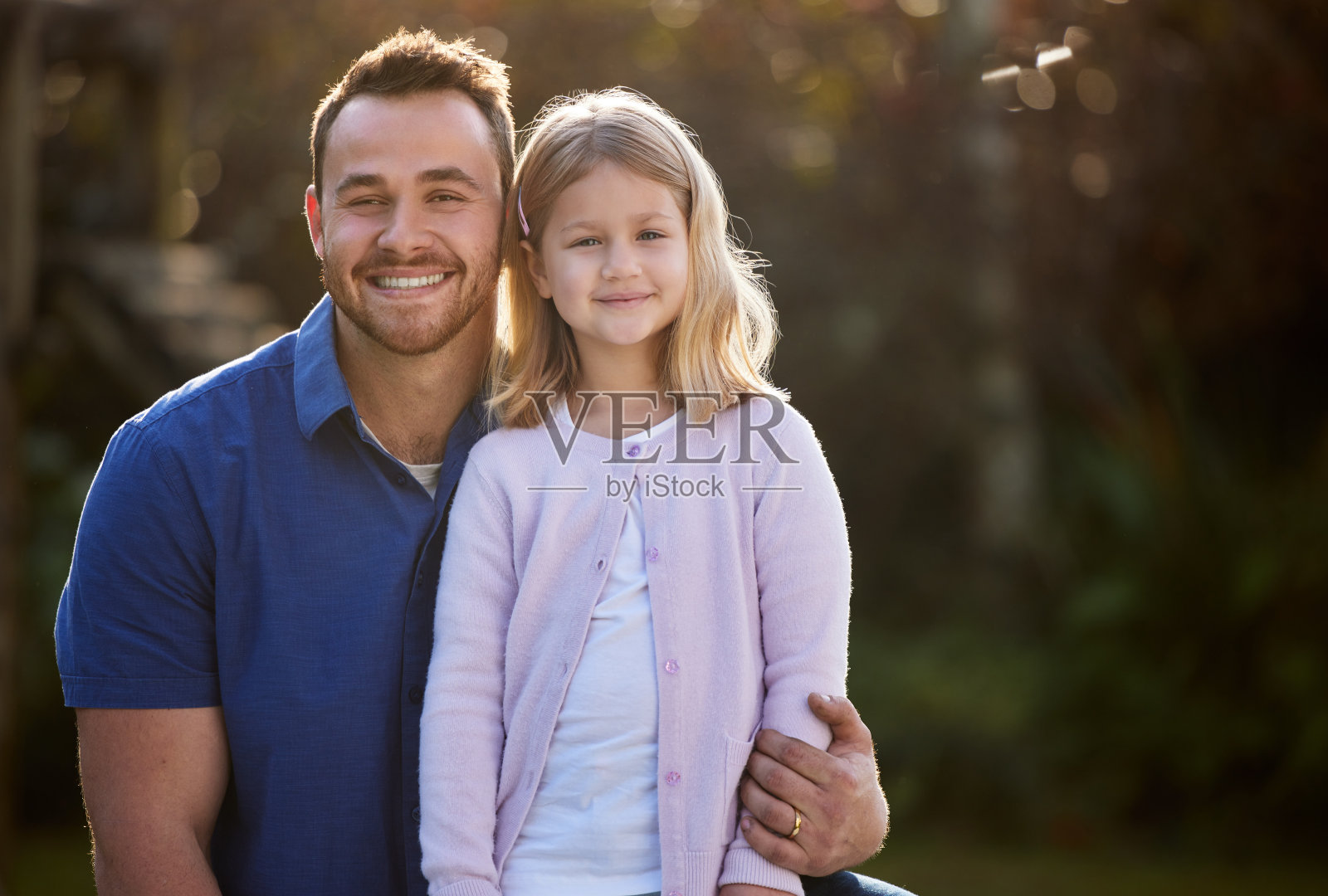 一个英俊的年轻男子和他的女儿在外面的花园里摆姿势照片摄影图片
