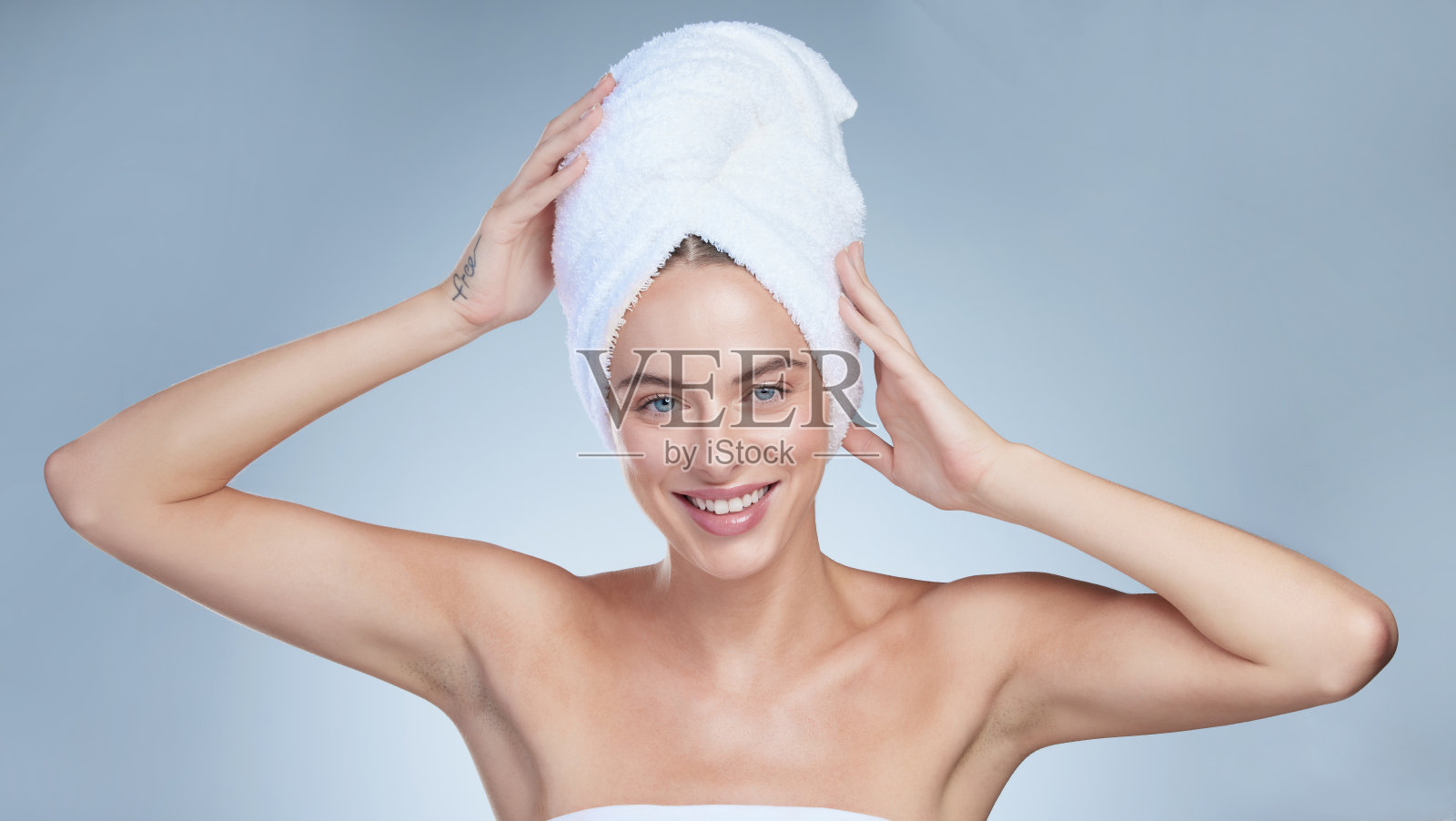 一个迷人的年轻女子的工作室肖像与毛巾在她的头对灰色的背景摆姿势照片摄影图片