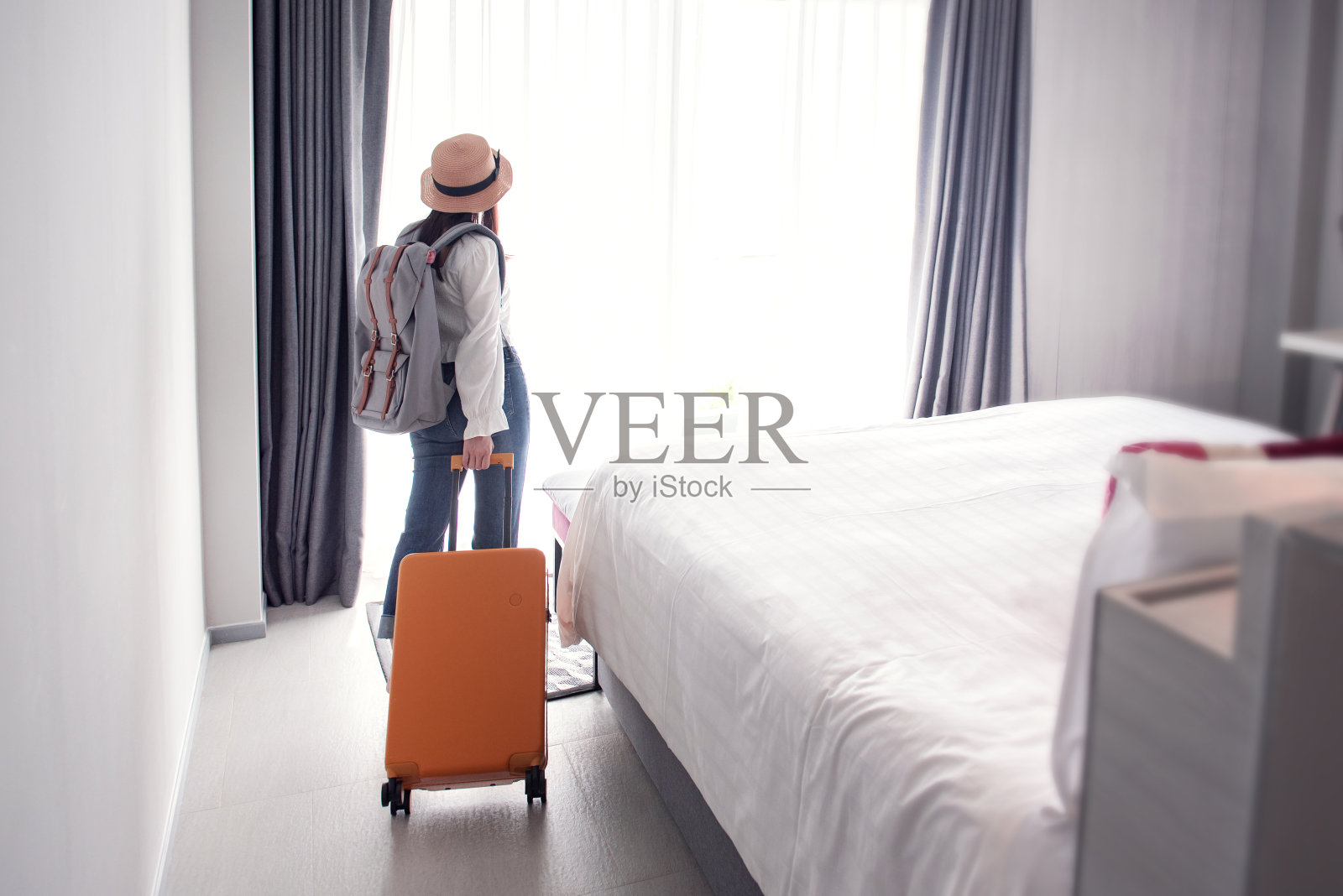 女游客在入住后带着行李进入酒店。旅游度假的概念。照片摄影图片