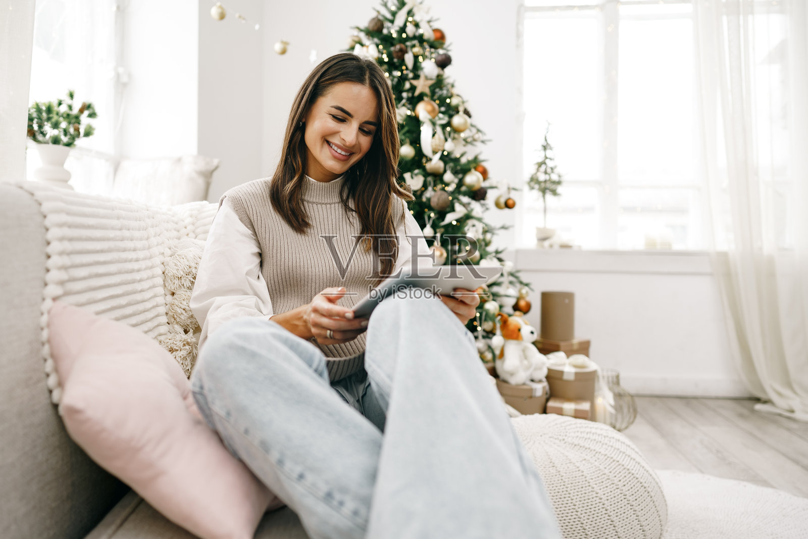 圣诞节的时候，漂亮的女人在沙发上摆弄着数码平板电脑照片摄影图片